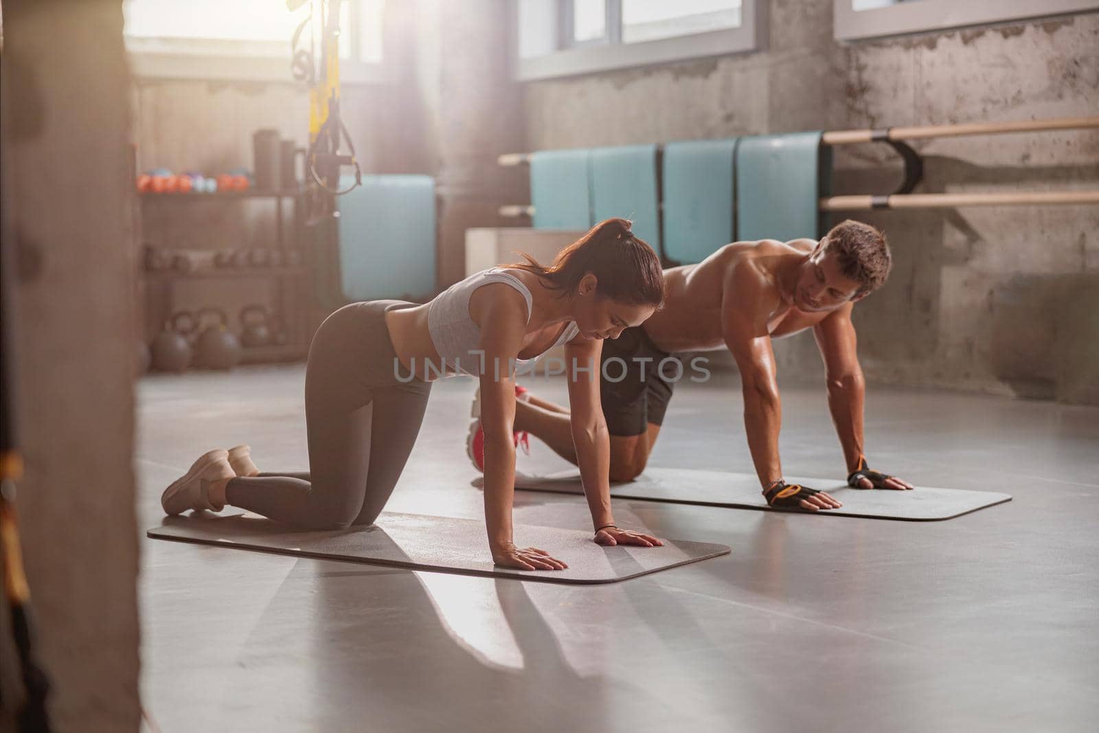 Sporty woman and athletic man performing sports exercise plank on yoga mat in the fitness club