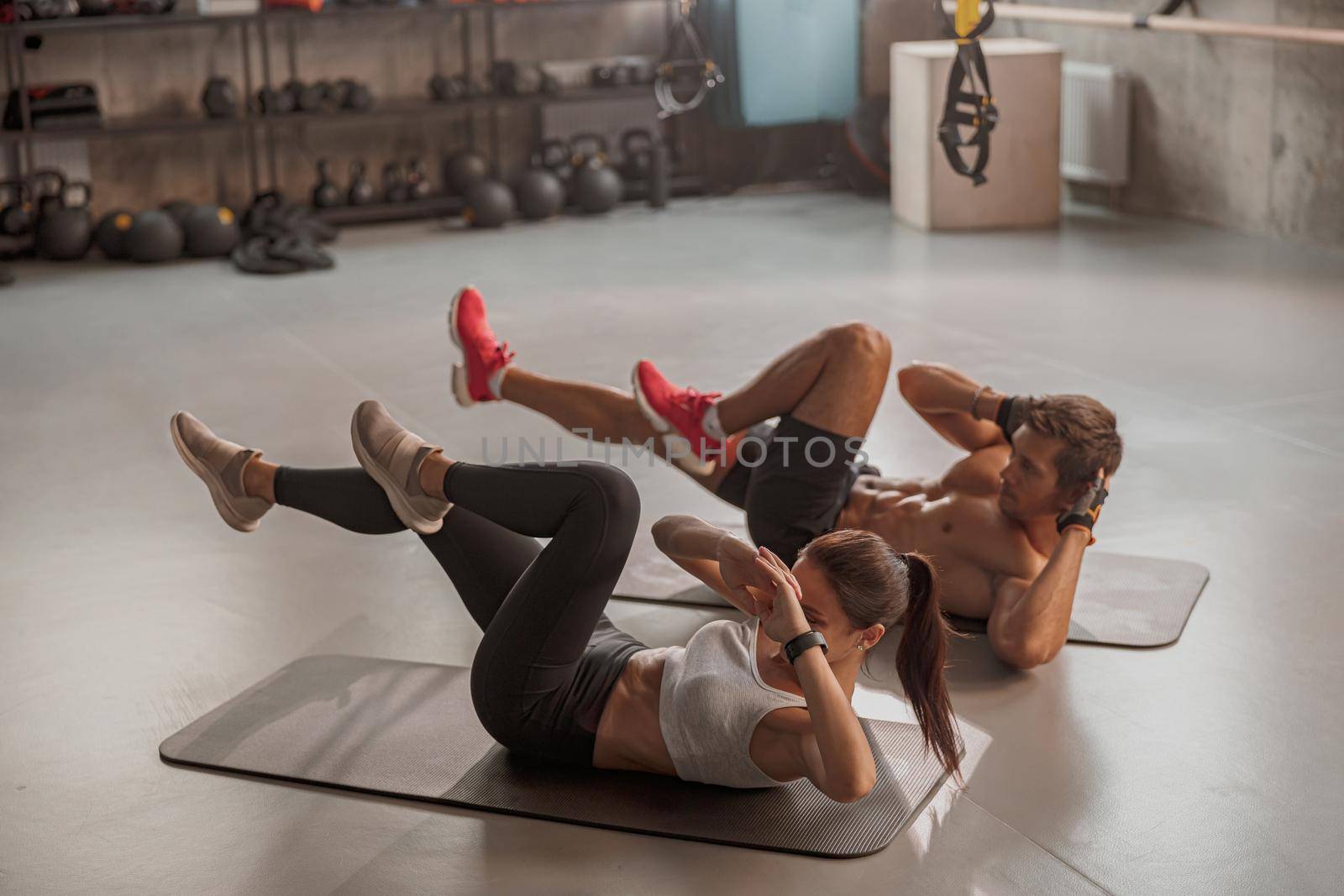Man and woman doing exercises laying on the yoga mat by Yaroslav_astakhov