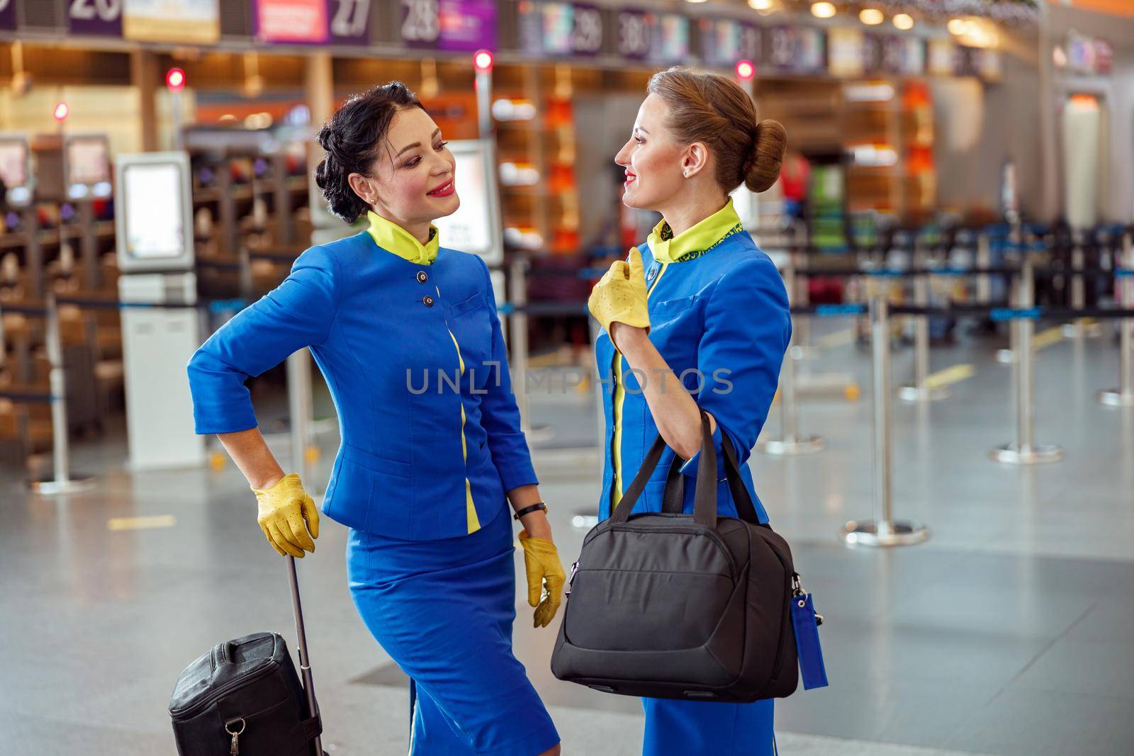 Cheerful flight attendants standing in airport terminal by Yaroslav_astakhov