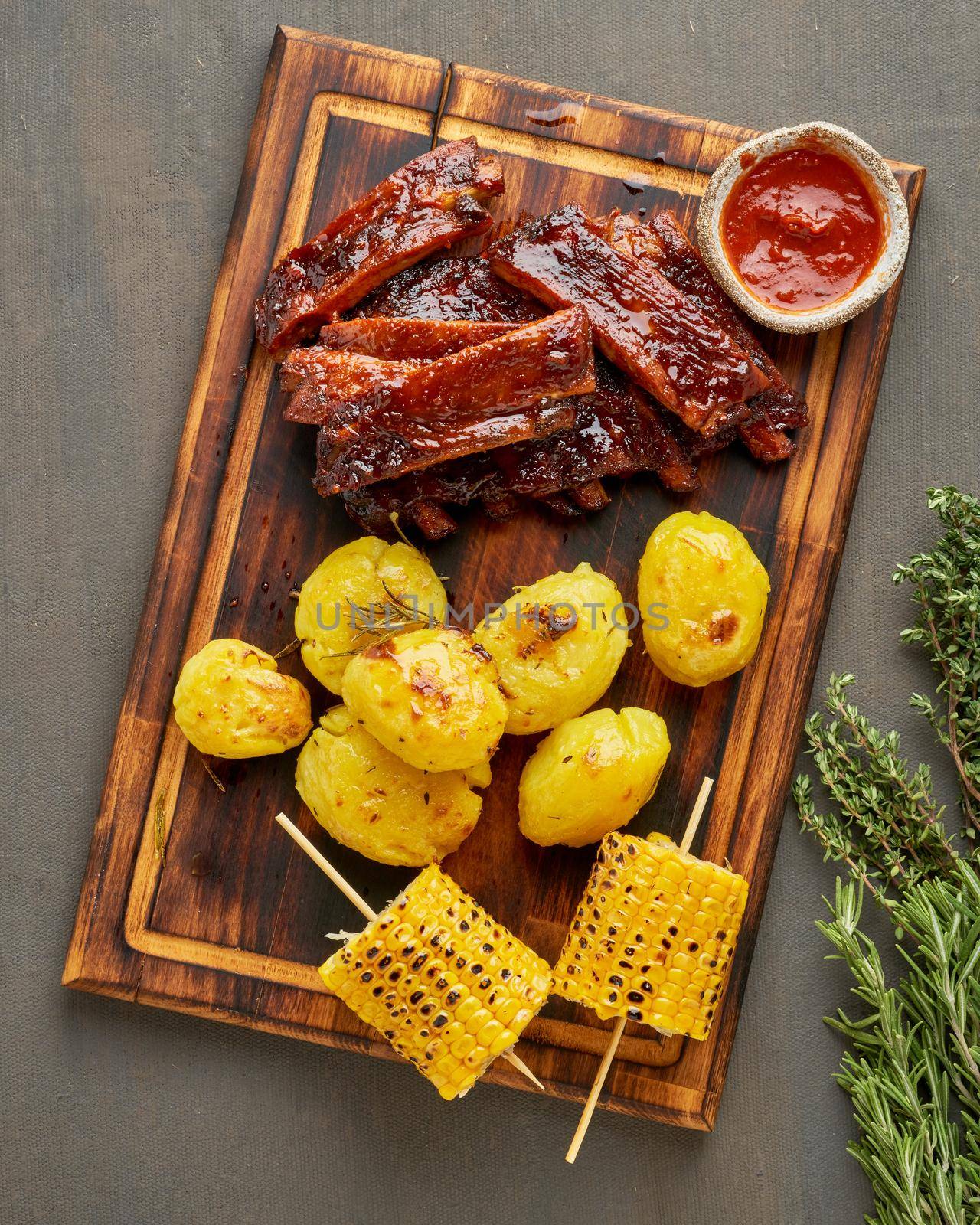 Spicy barbecue pork ribs, corn ears and crushed smashed potatoes. Slow cooking recipe. Pickled Roasted Pork Meat with red sauce. American Cuisine. Vertical