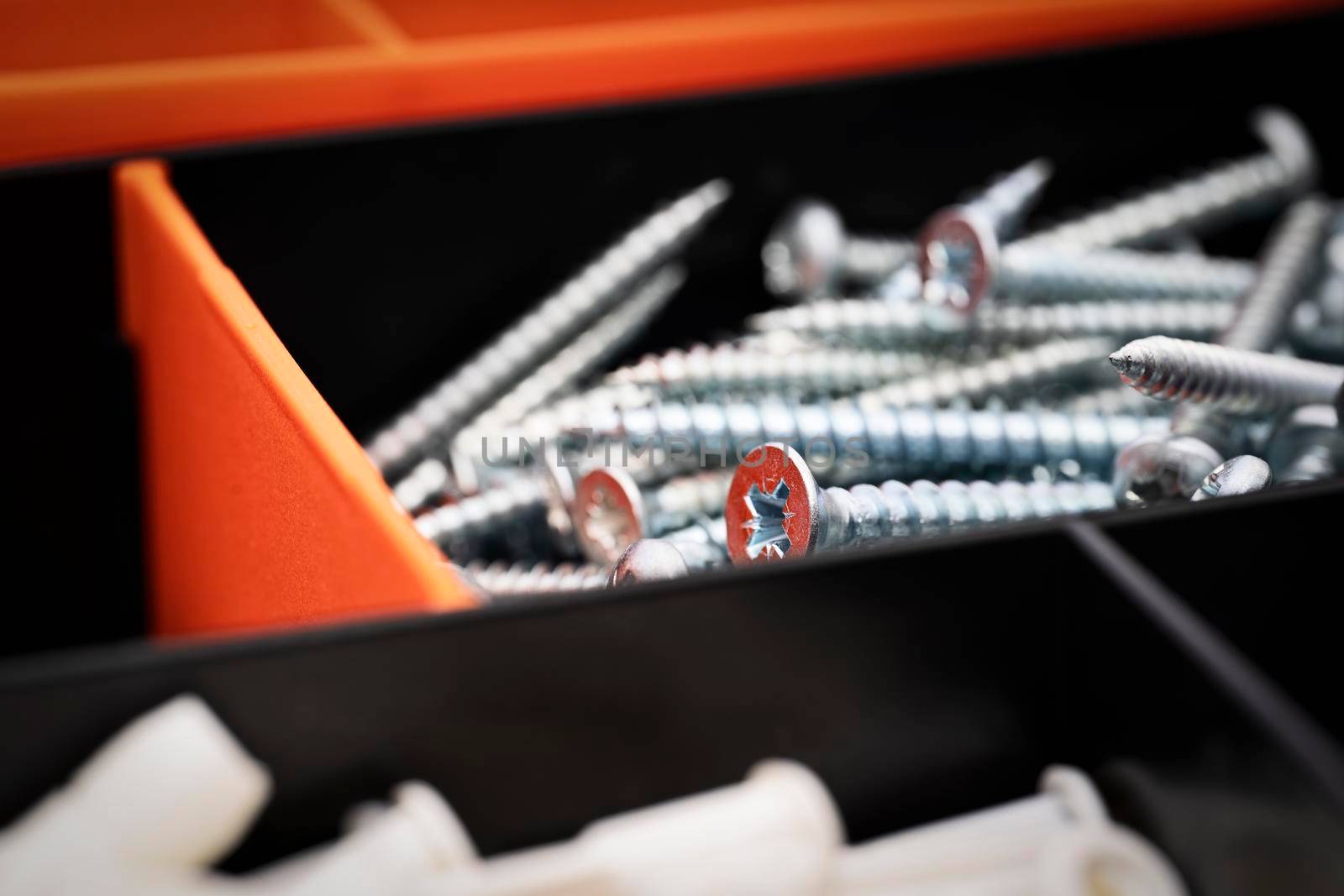 Close up of pile of metal screws in a toolbox by Mendelex