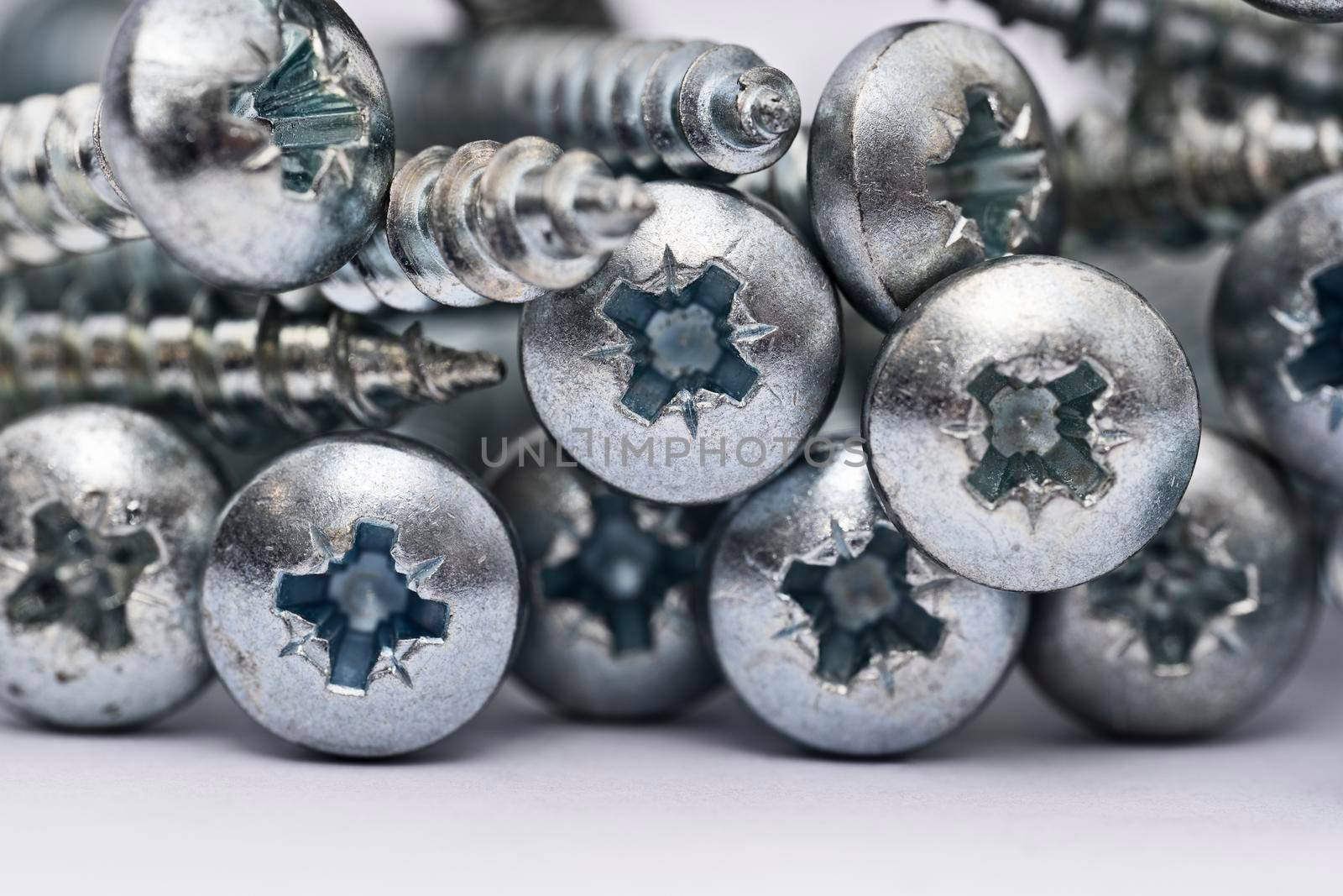 Close up of a pile of multipurpose metal screw heads by Mendelex