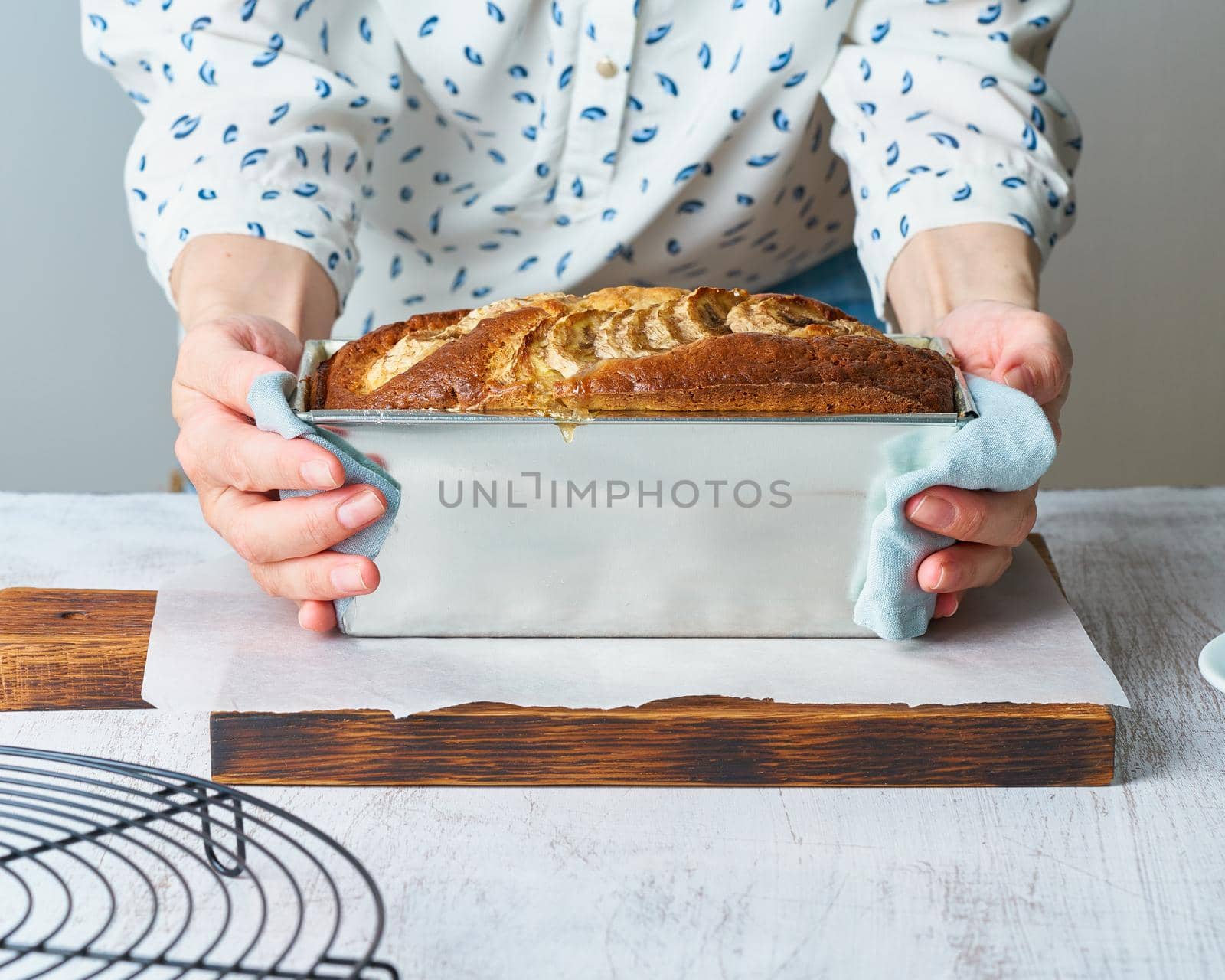 Banana bread in loaf pan. Cake with banana, traditional american cuisine. Whole loaf. Dark background, black table, shadows. Side view