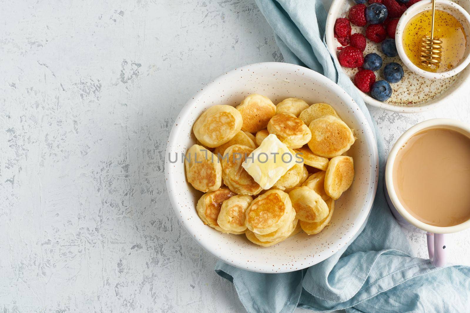 Pancakes cereal, tiny thin funny crumpet, children's food. Breakfast with drink, white table, bright morning, top view, copy space