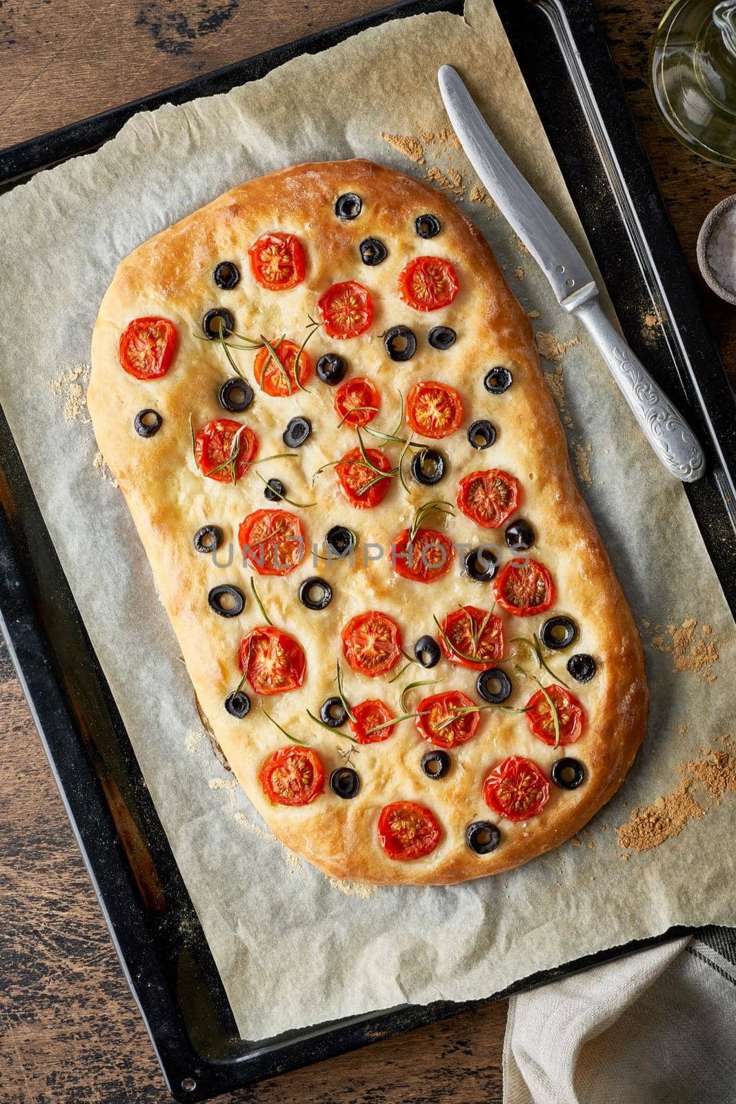 Focaccia, pizza, italian flat bread with tomatoes, olives and rosemary on tray by NataBene