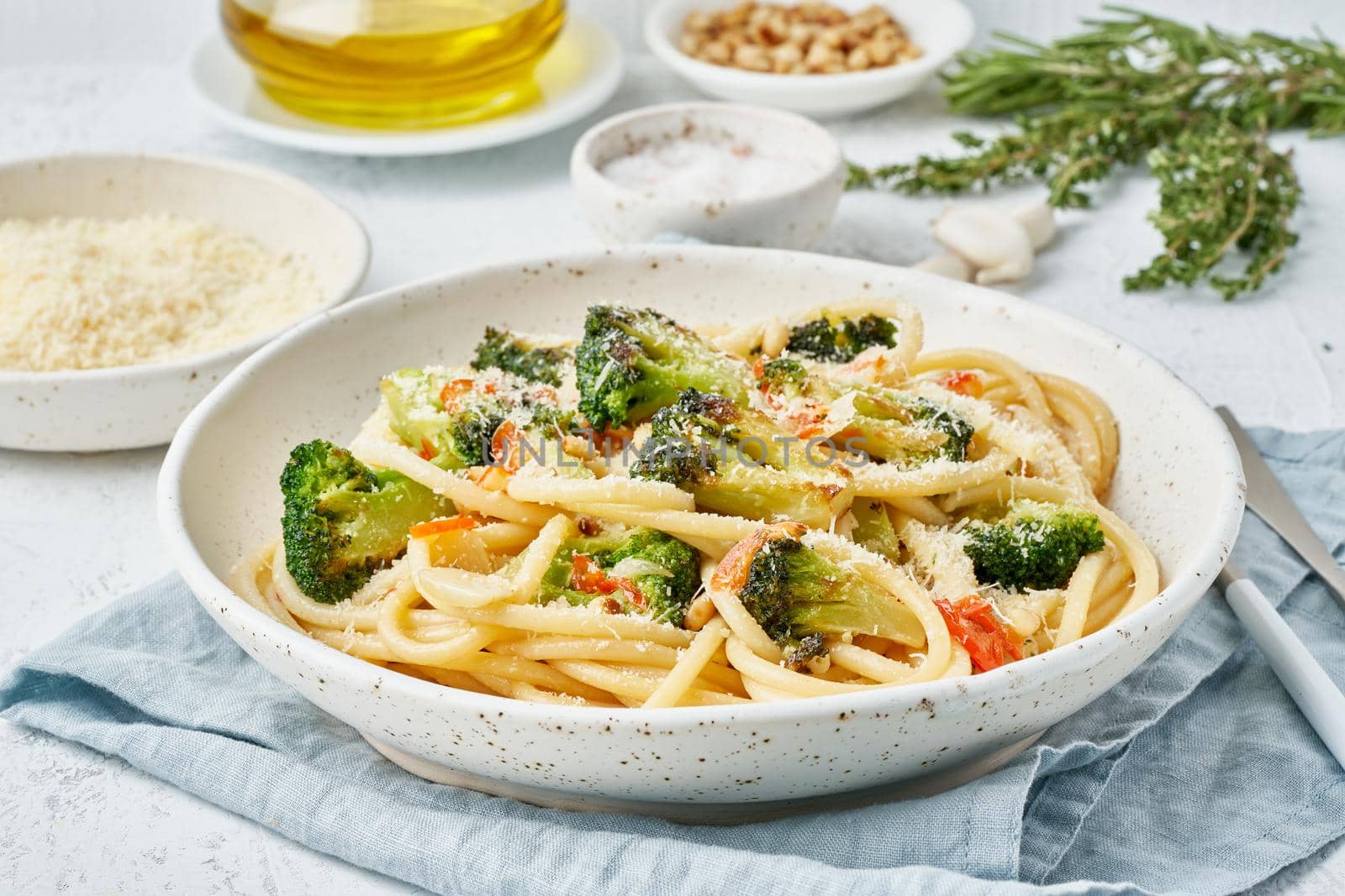 Spaghetti pasta with broccoli, bucatini with peppers, garlic, pine nuts. Food for vegans, vegetarians. Healthy dietary Mediterranean food. Light white table. Side view