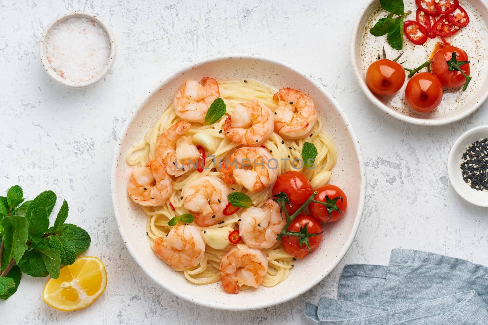 Pasta bavette with fried shrimps, bechamel sauce, mint leaf, garlic, on white plate, top view by NataBene