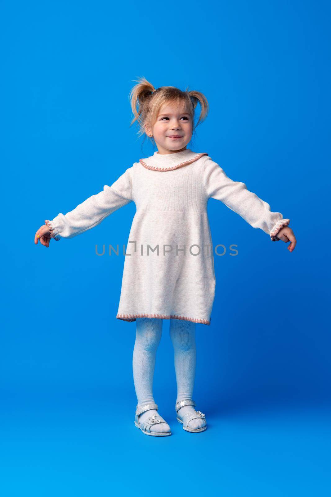 Full length portrait of a little girl standing on blue backgorund, close up