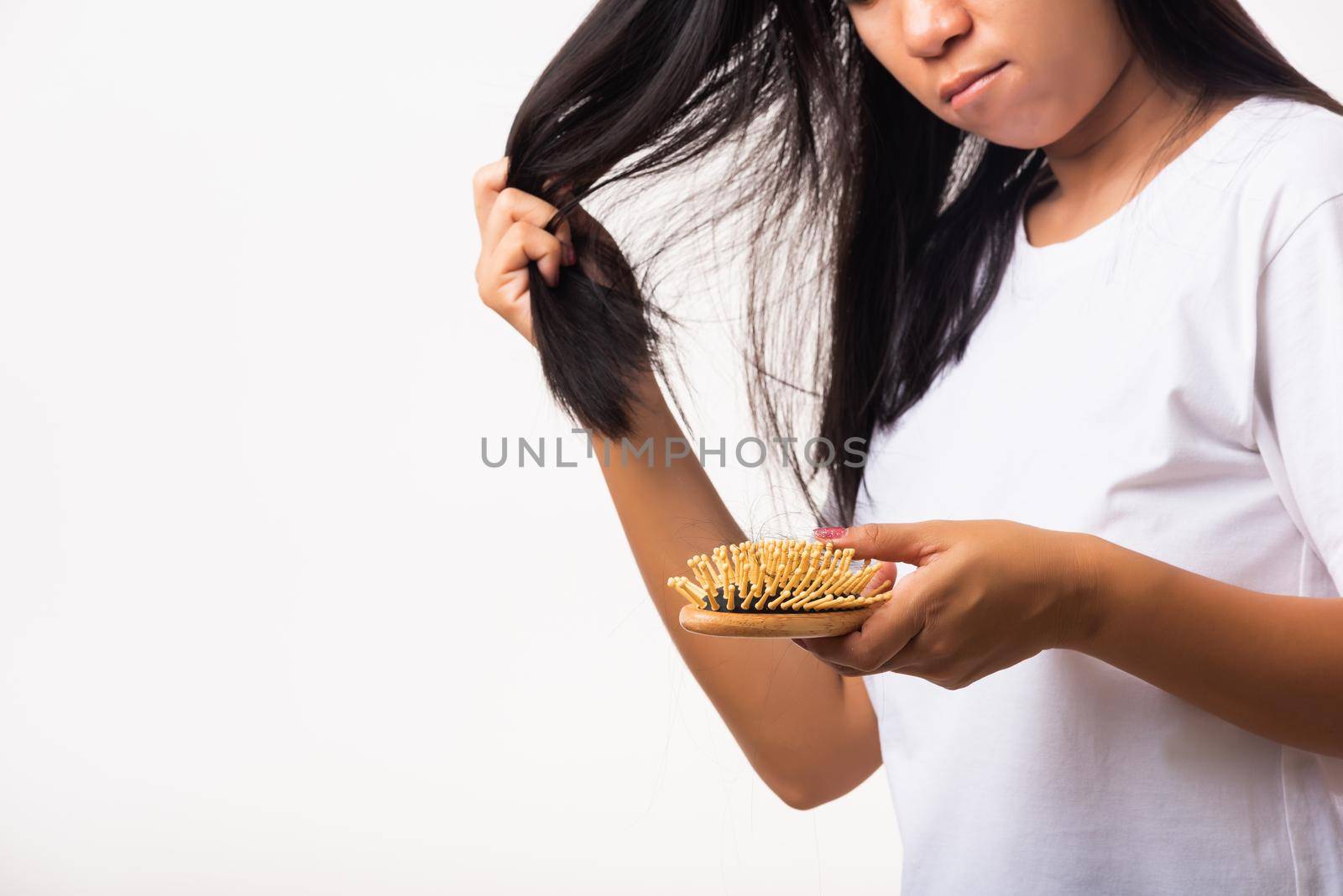 Asian woman unhappy weak hair her hold hairbrush with damaged long loss hair in the comb brush on hand and she looking to hair, studio shot isolated on white background, medicine health care concept