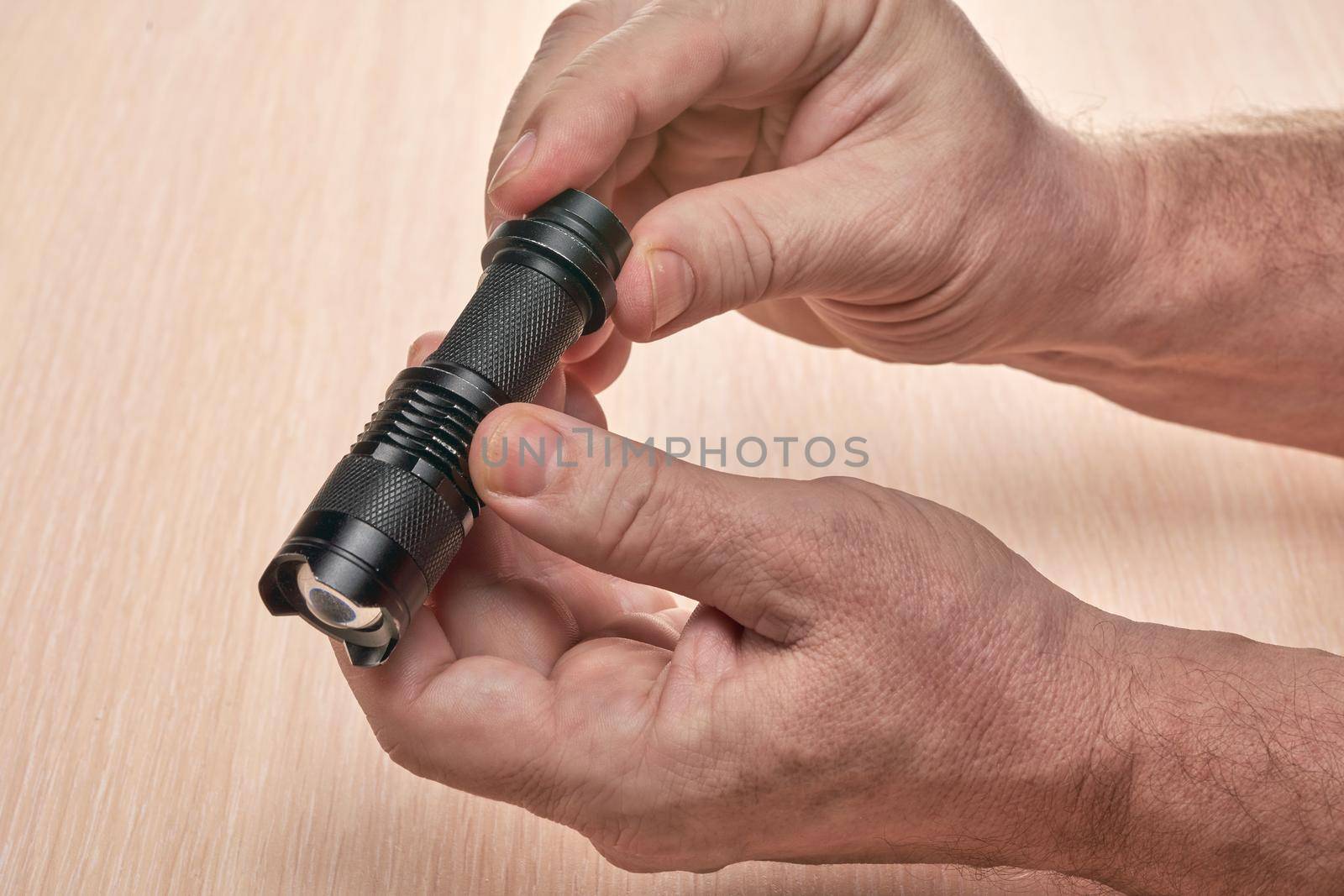 Hands hold a small black flashlight to replace the used battery by vizland