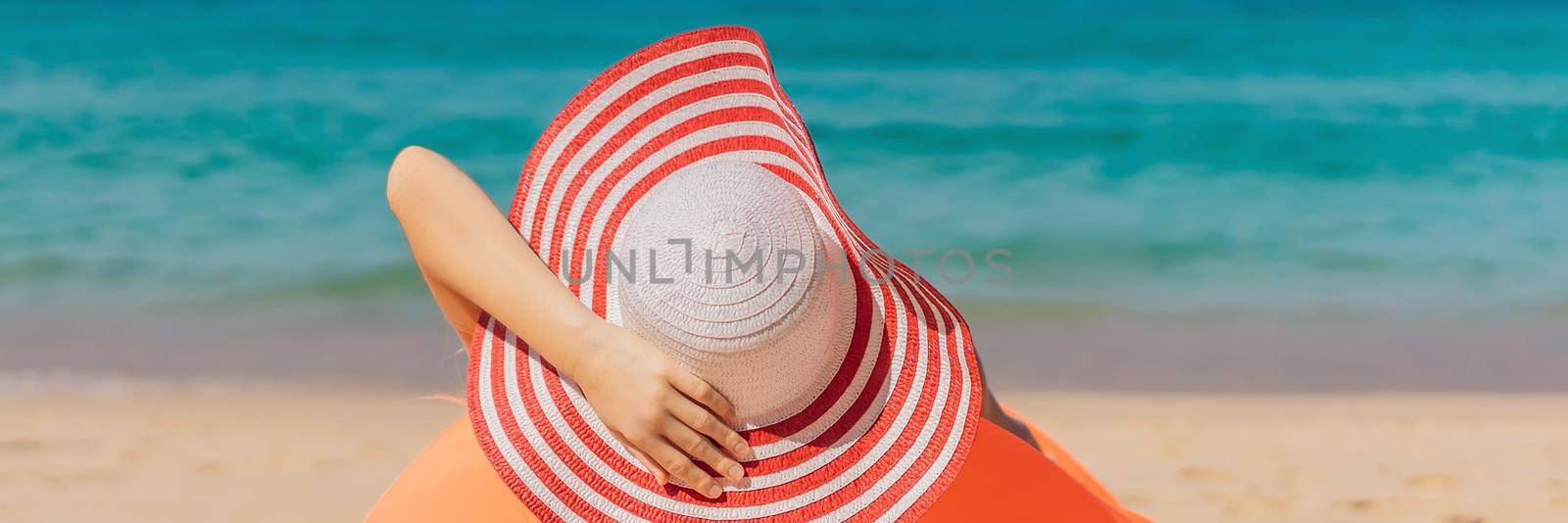 Summer lifestyle portrait of pretty girl sitting on the orange inflatable sofa on the beach of tropical island. Relaxing and enjoying life on air bed. BANNER, LONG FORMAT