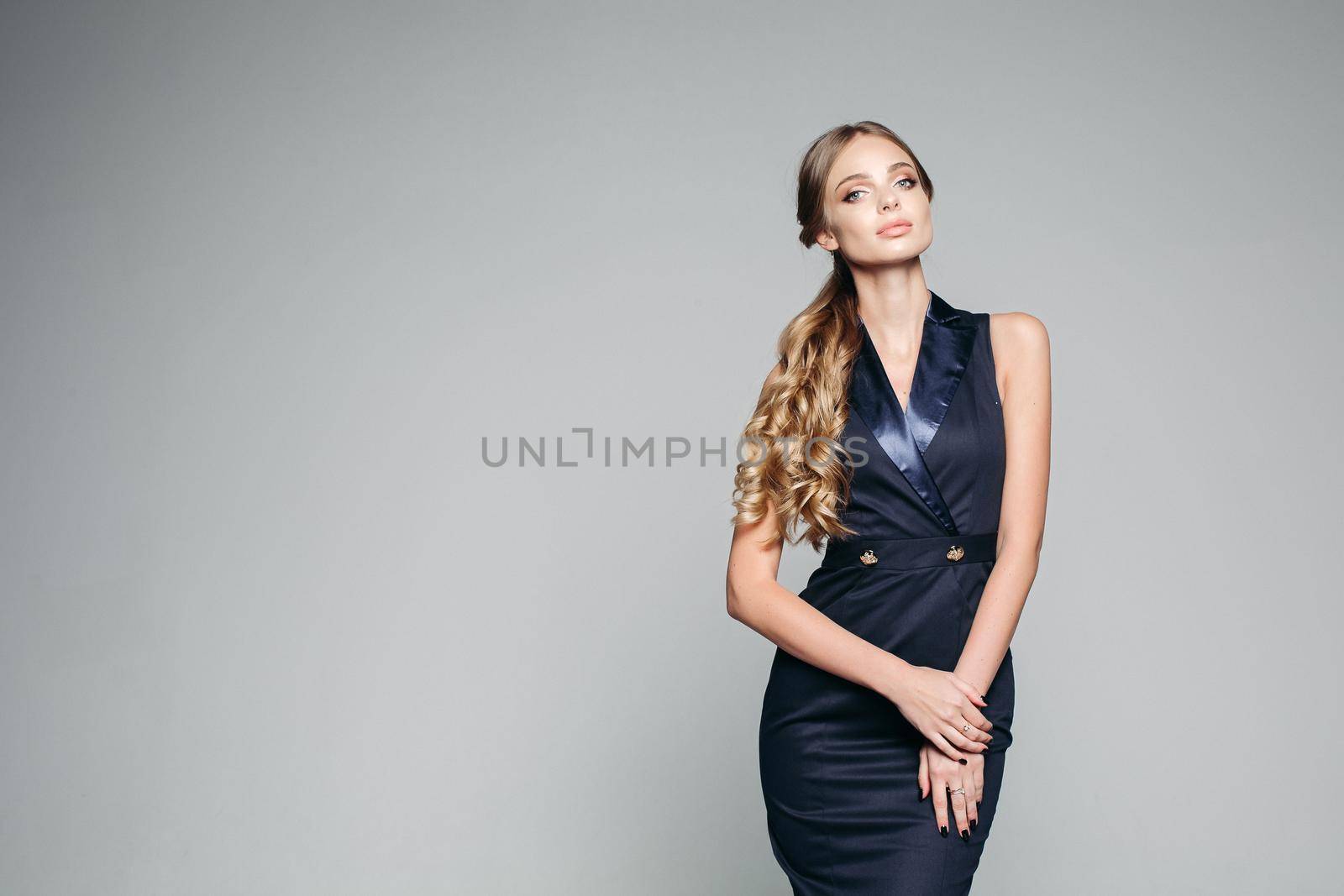 Studio portrait of serious and seductive woman wearing in elegant dark blue dress, with perfect make up and stylish hairstyle after beauty salon. Concept of fashion, style and shopping sale.