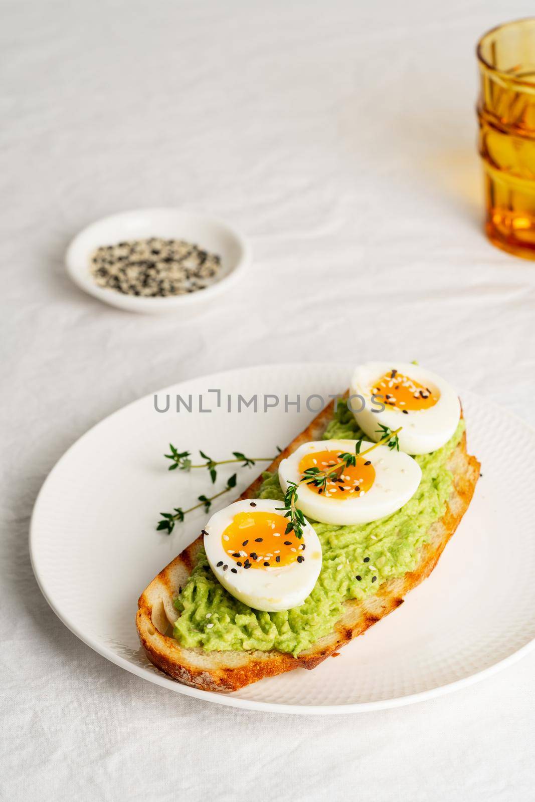 Avocado toast with toasted bread soft-boiled eggs with herbs by NataBene