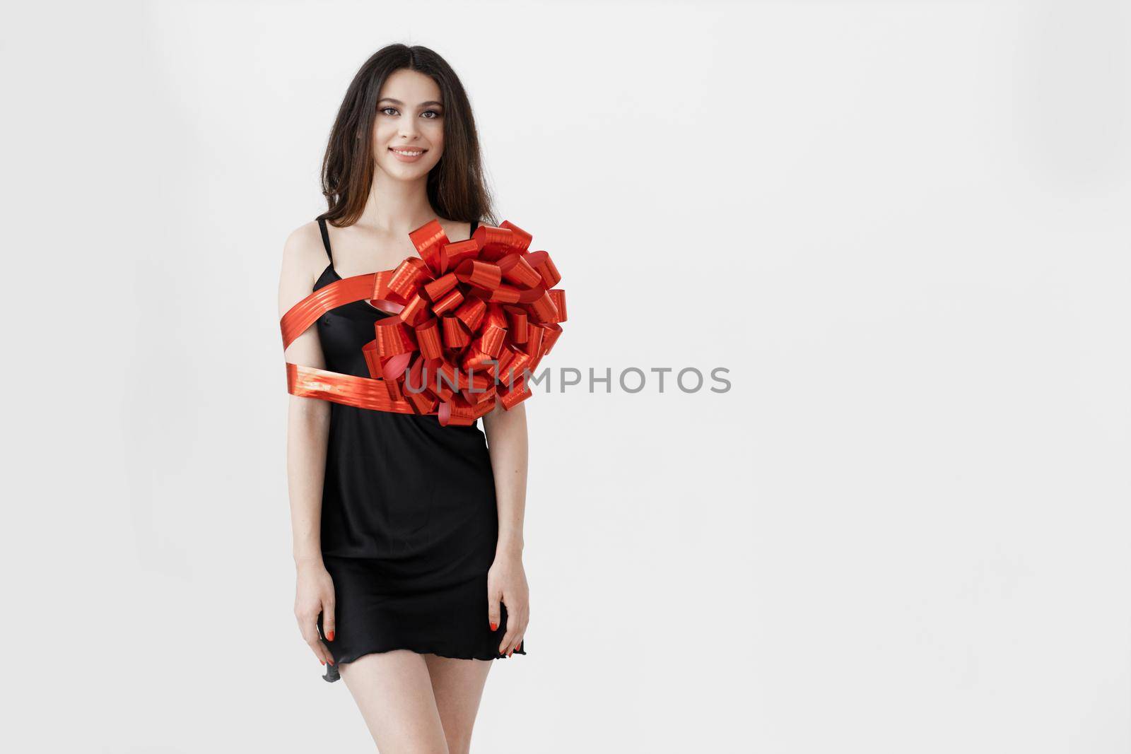 Young pretty woman wrapped with ribbon, red gift ribbon. High quality photo