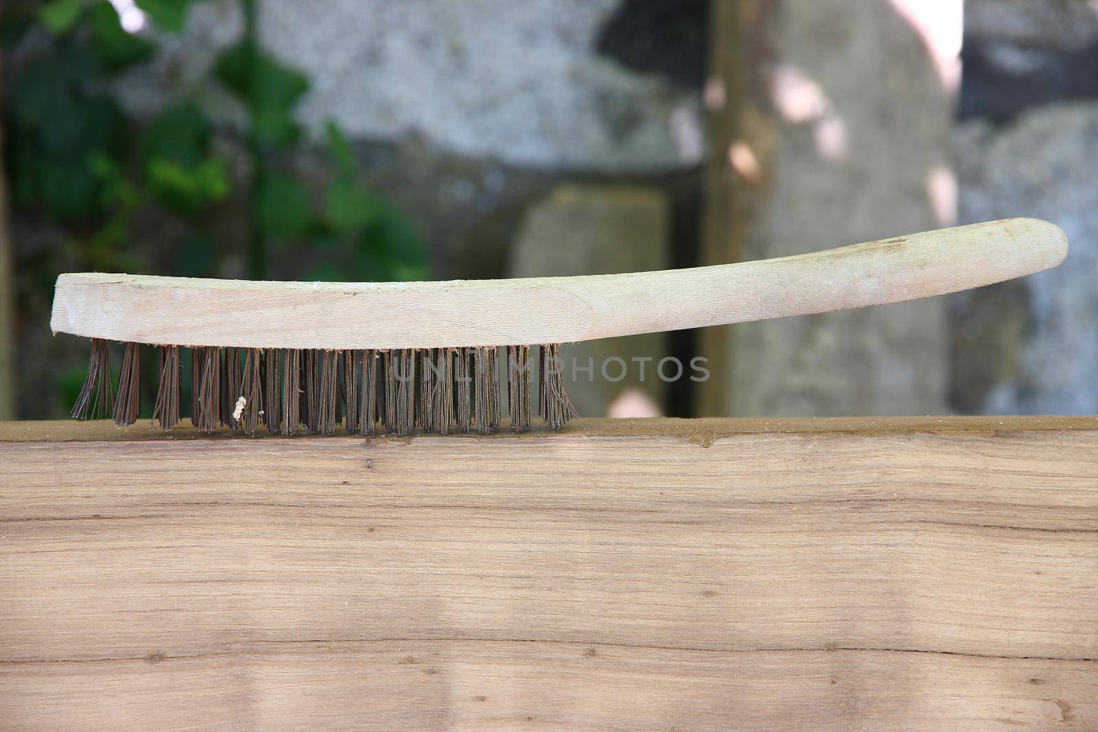 Wire brush over wood closeup with iron bristles