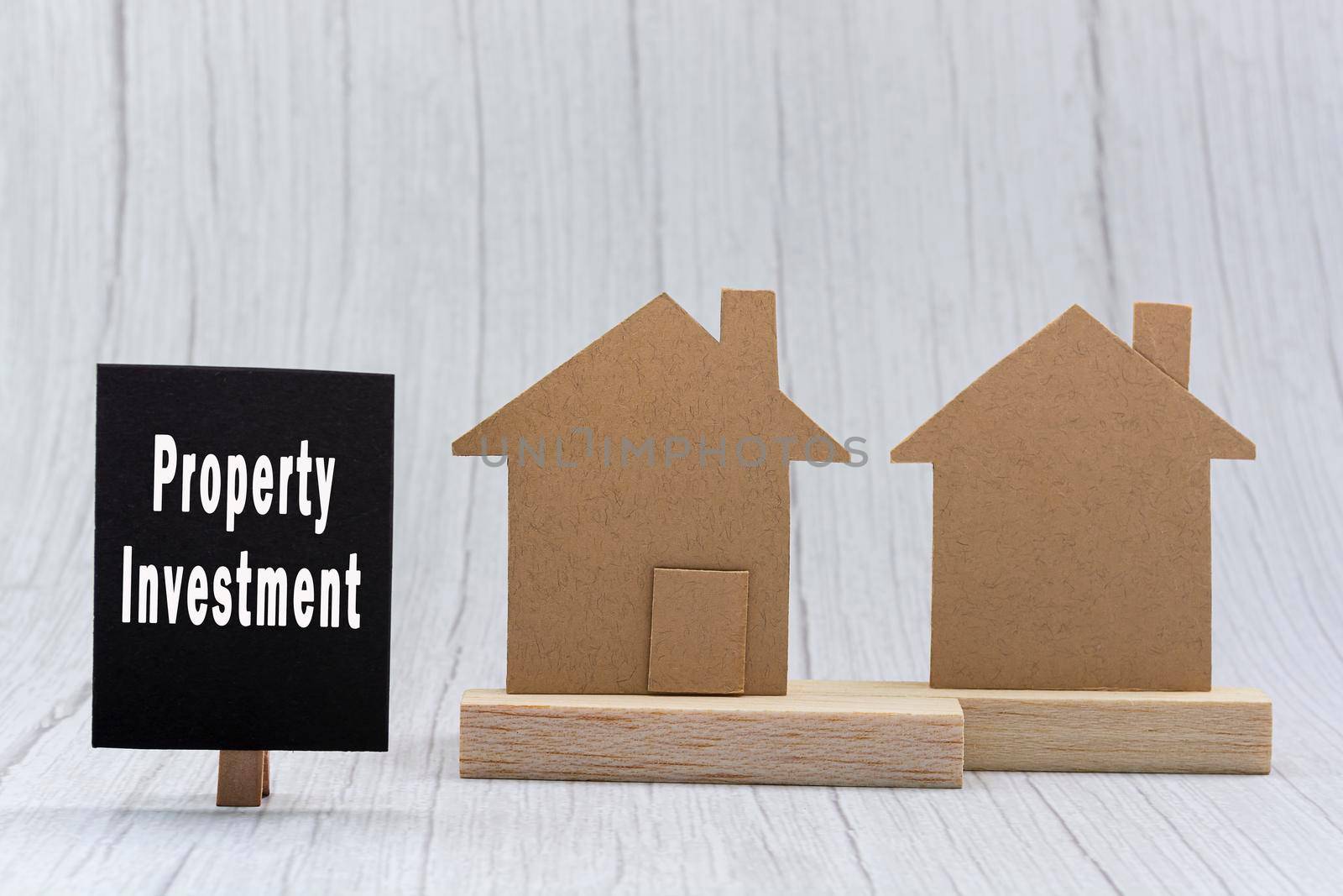 Investment property text on black note with house model on white wooden background. Concept for real estate property investment.