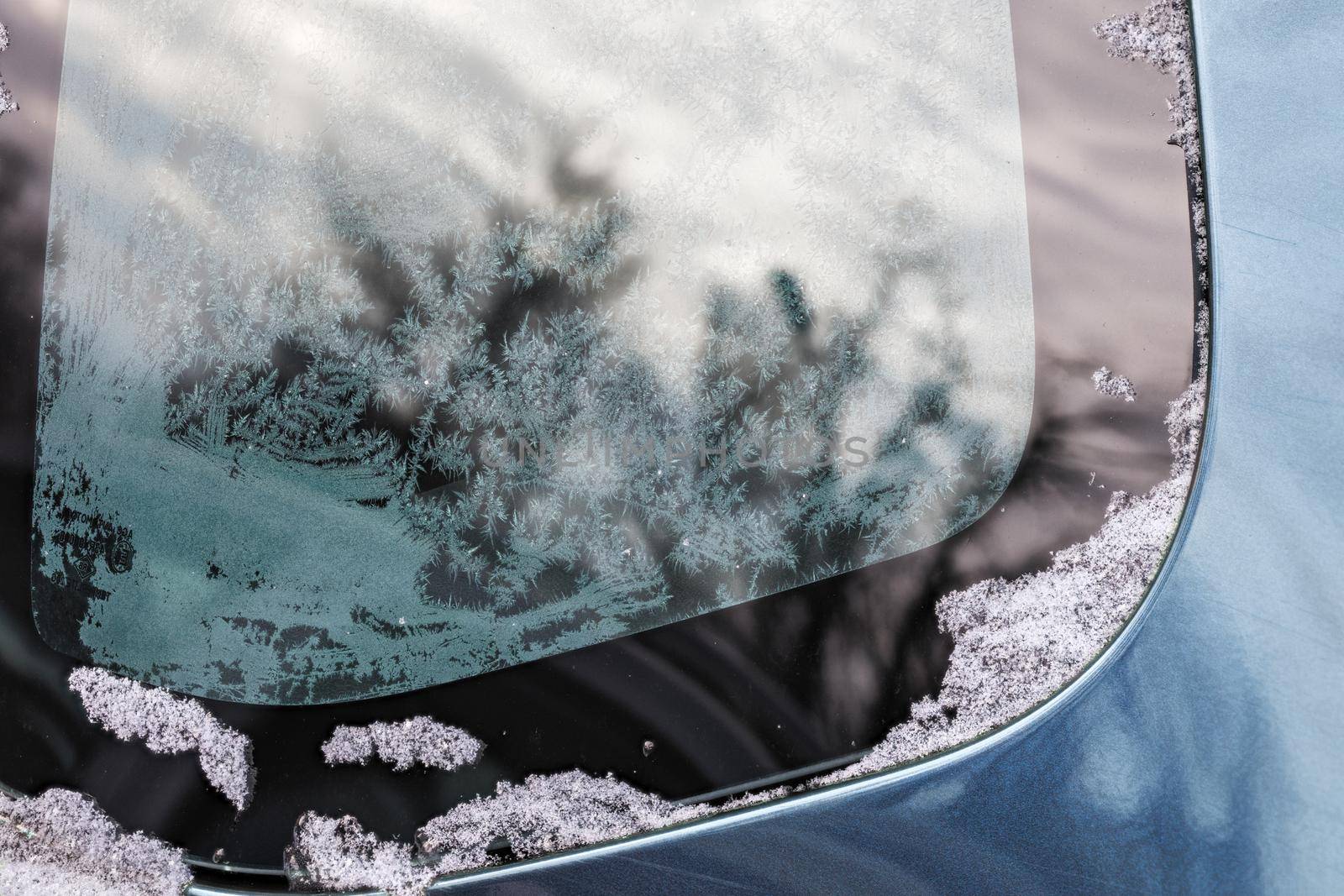 winter hoarfrost pattern on car window glass at daylight close-up with selective focus and shallow depth of field