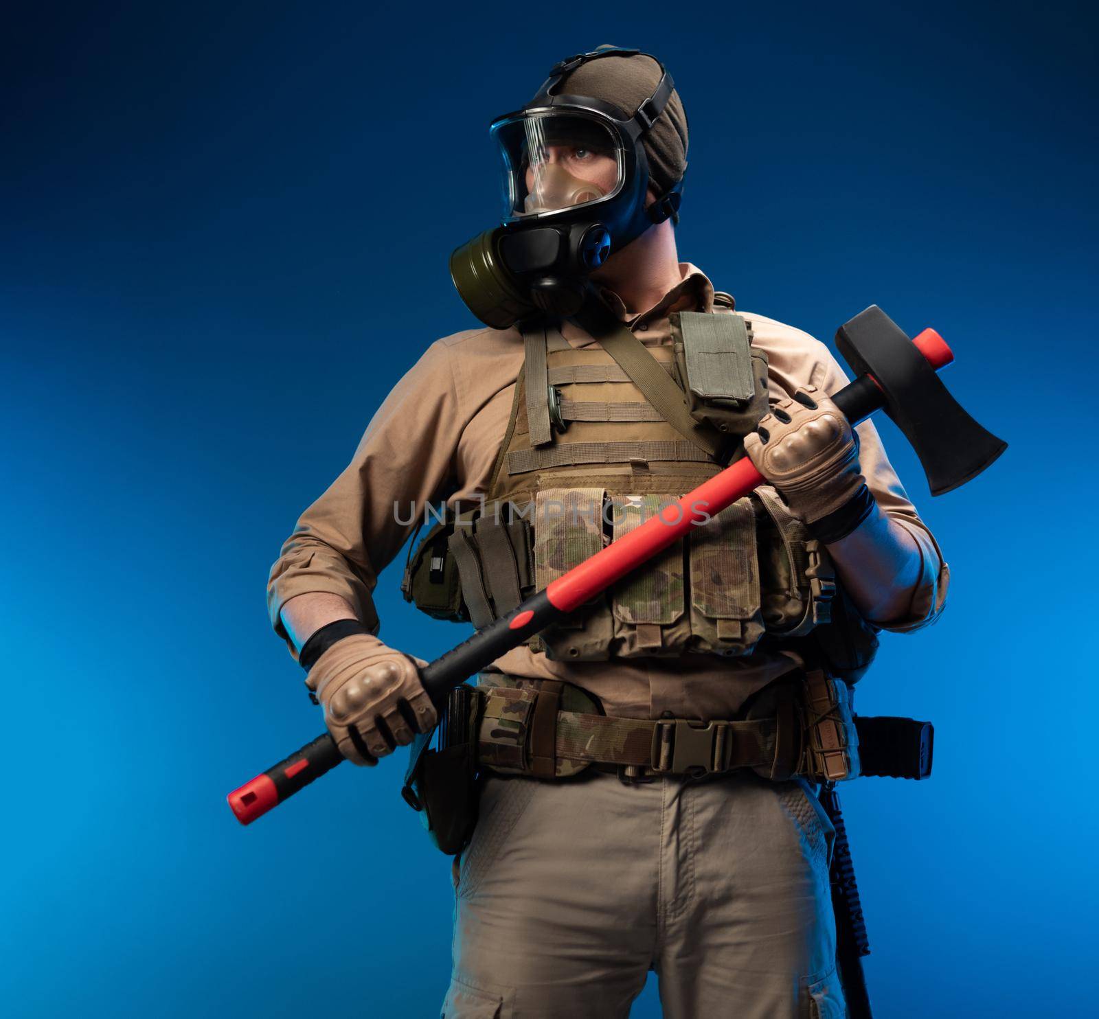 a soldier in military clothes with a bulletproof vest in a gas mask holds a red fire axe in his hands by Rotozey