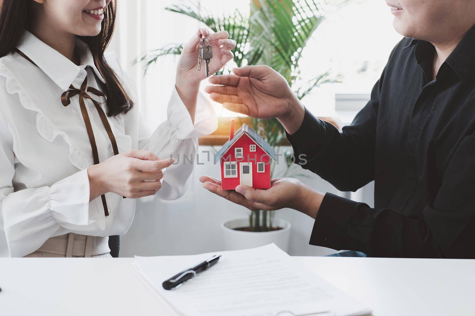 Close up of Business woman giving house key after signing agreement for buying house. Bank manager and real estate concept. by itchaznong