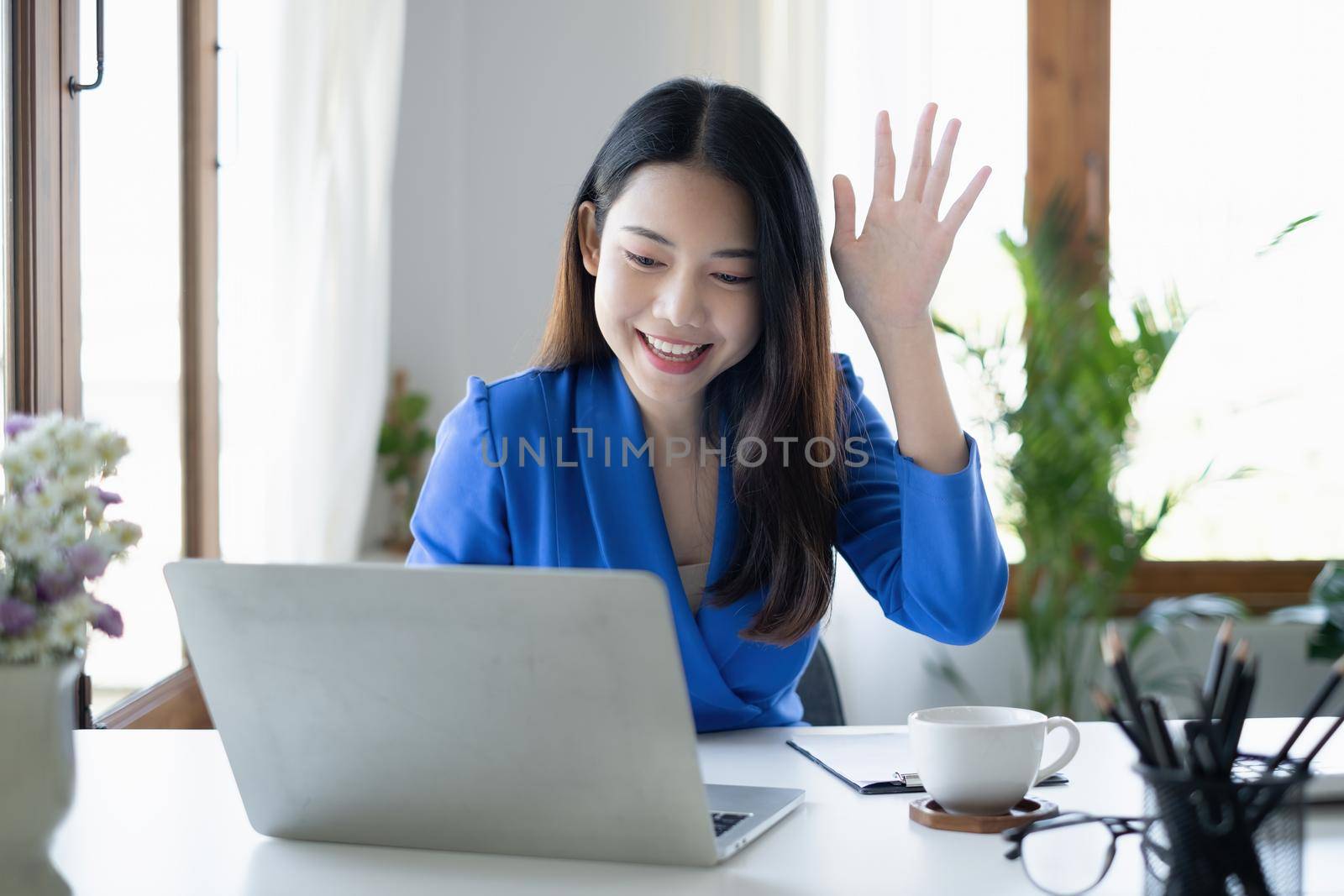 Asian Woman blogger wear blue suit talking with followers, live streaming on social media application. Freelance work from home concept. by itchaznong