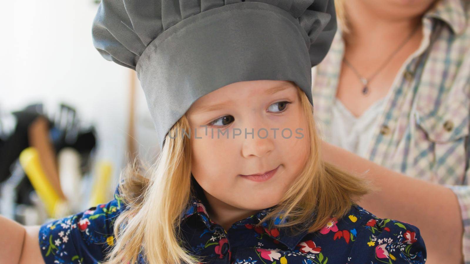 Cute little girl chef in hat smiling at cooking studio, horizontal