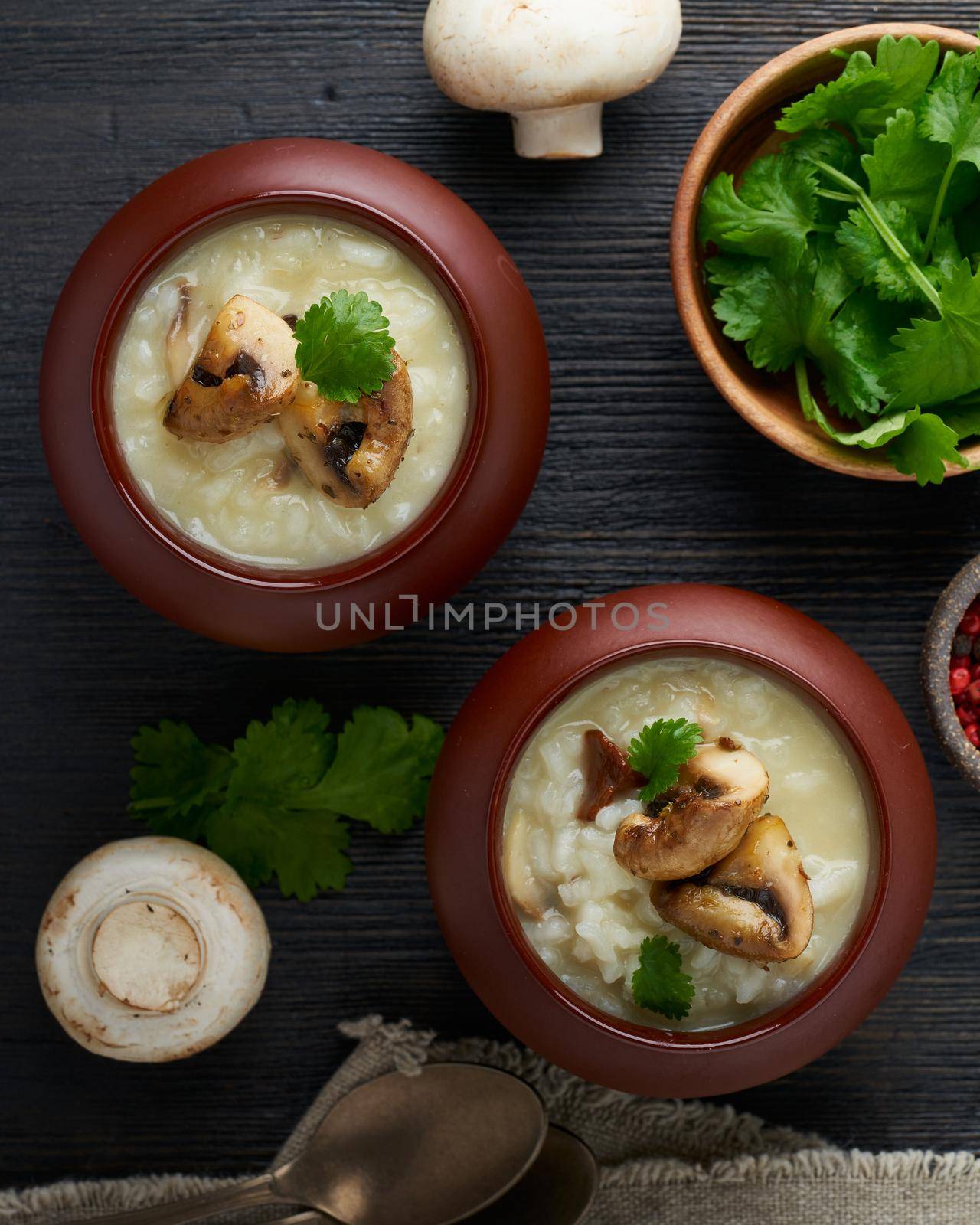 Unconventional unusual serving of risotto with mushrooms in pot. Rice porridge with mushrooms. by NataBene