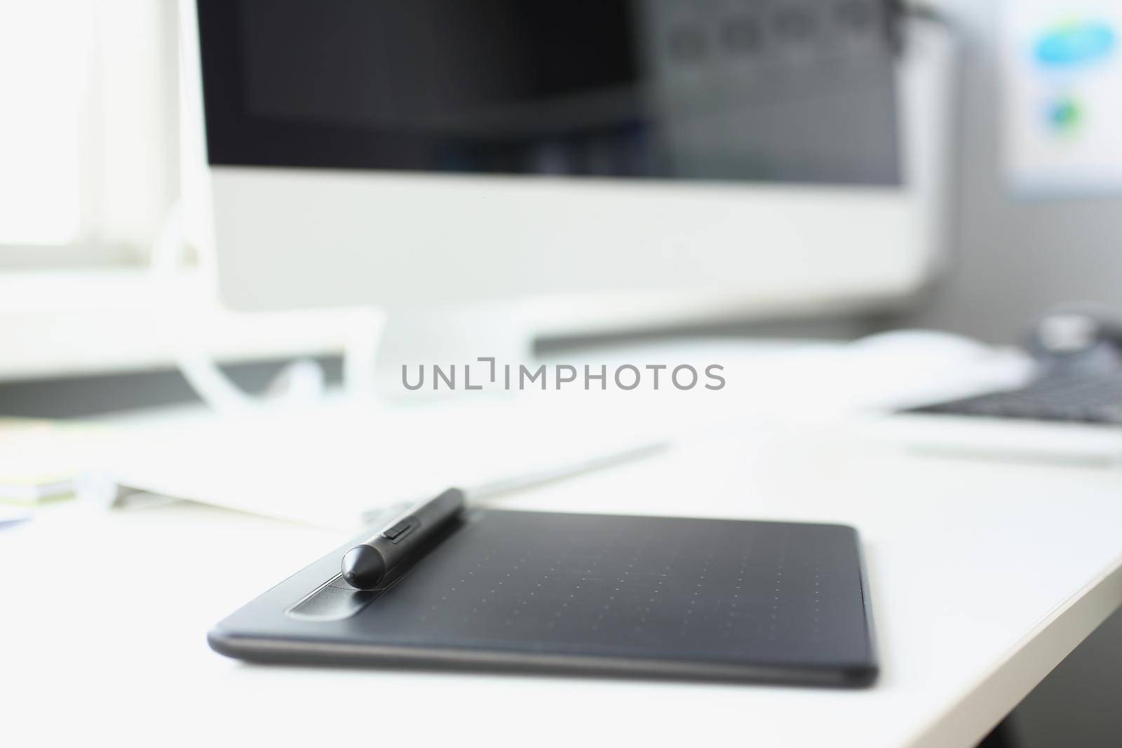 Close-up of modern workplace of designer with modern devices on table, tablet stylus and keyboard on table. Web graphic design, creativity, art concept