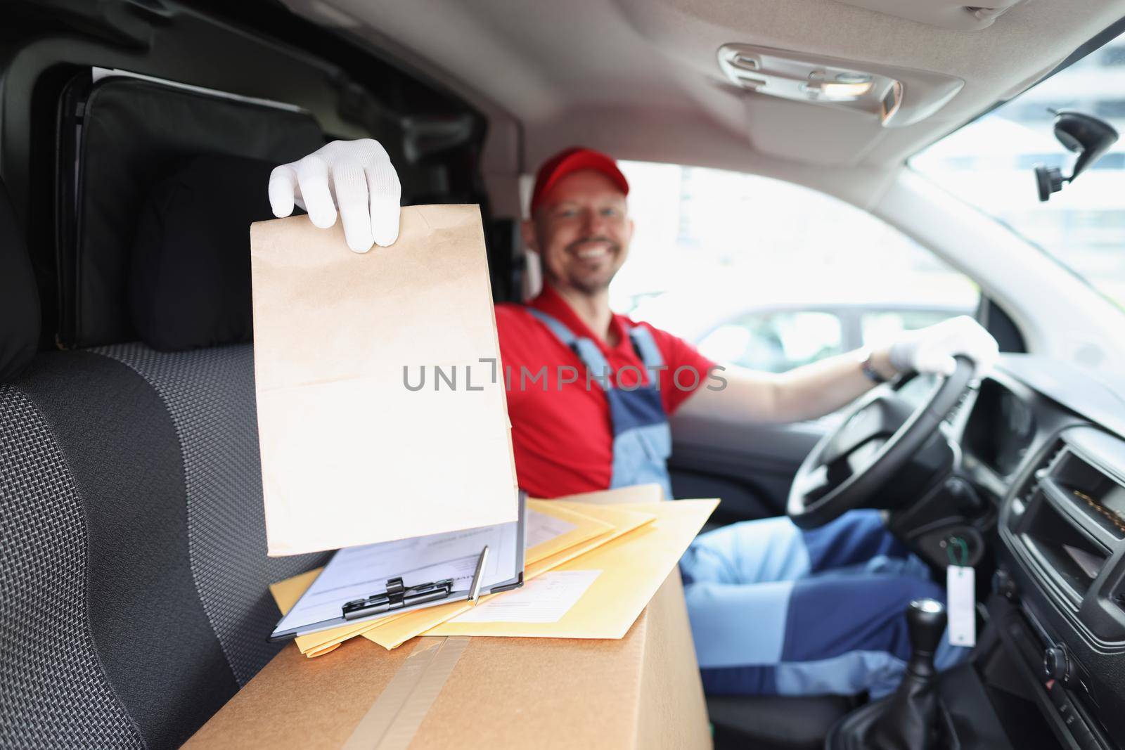 Portrait of courier hold package, delivery to owner on car, happy man in uniform. Worker deliver parcel fast on personal address. Delivery service concept