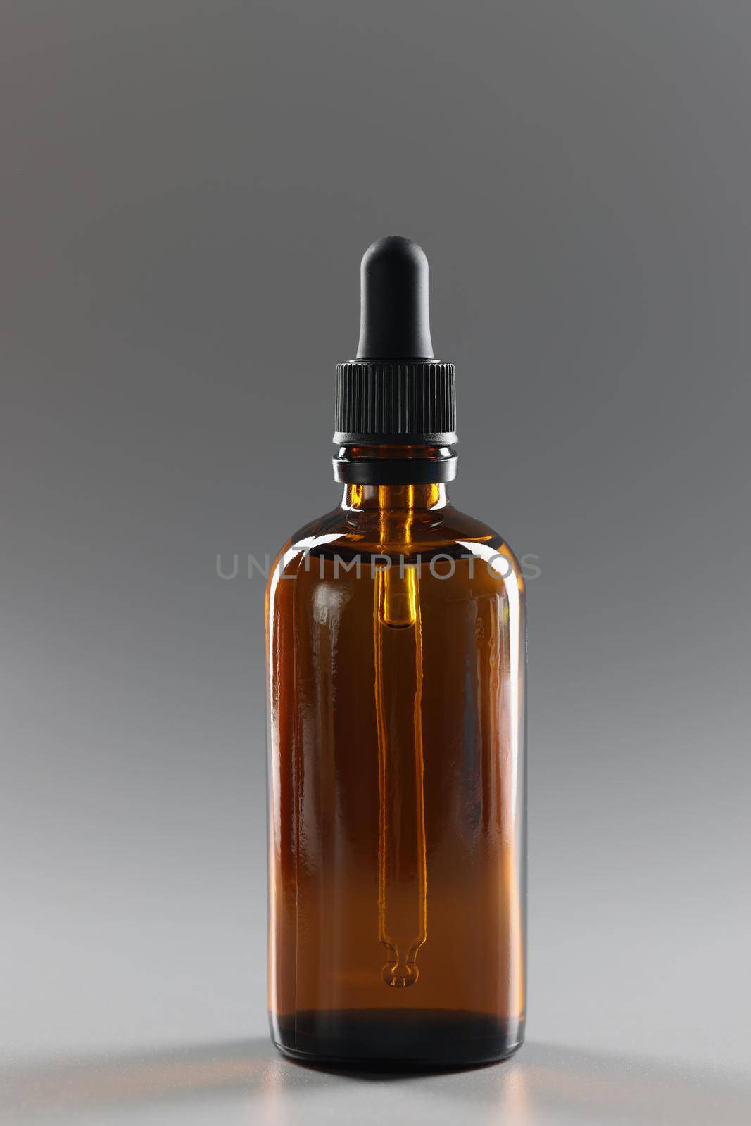 Close-up of brown glass bottle filled with oil, flask with cosmetology product or medication. Moisturizer, lotion for body and face. Cosmetology concept