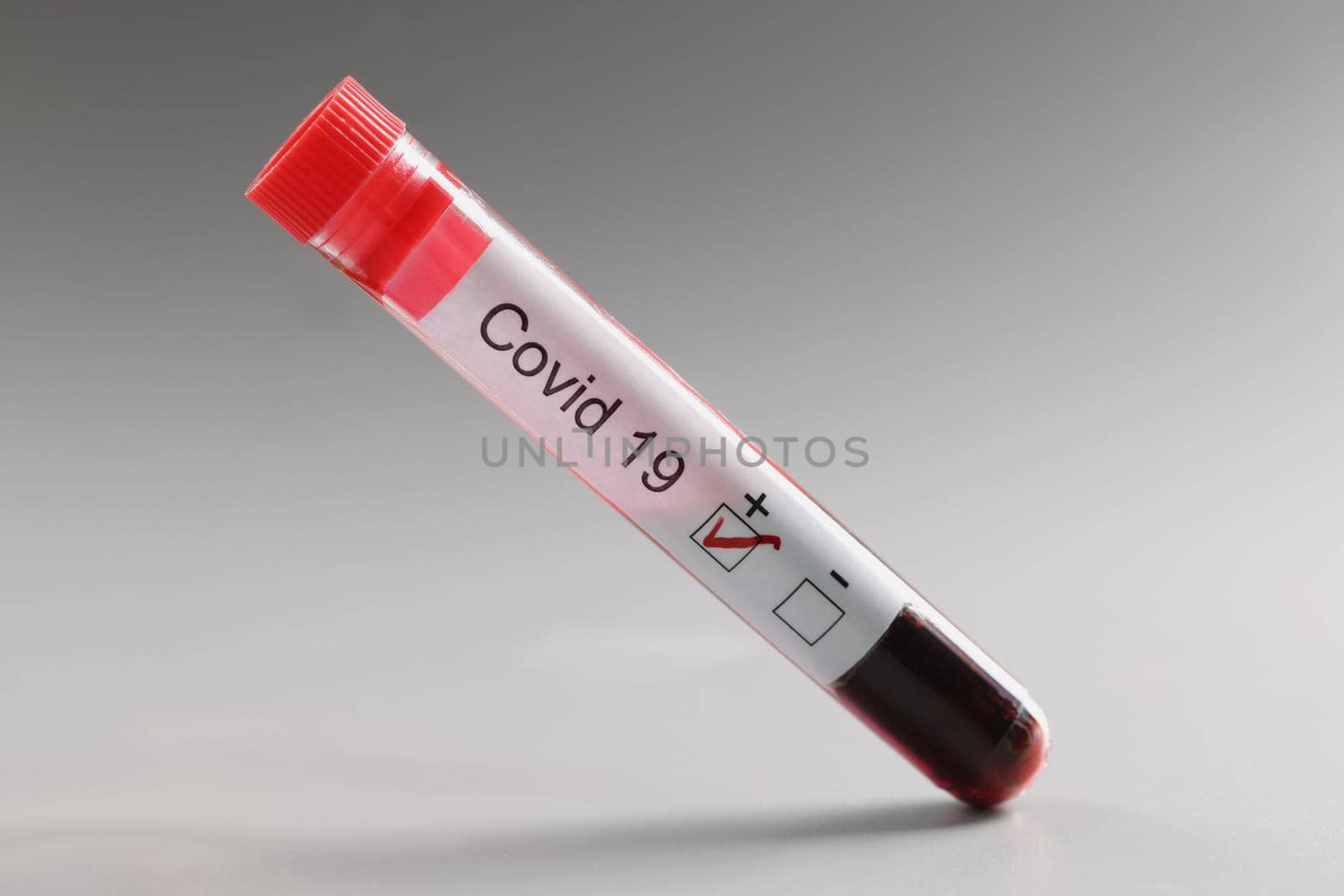 Test tube with coronavirus positive blood result on grey background by kuprevich