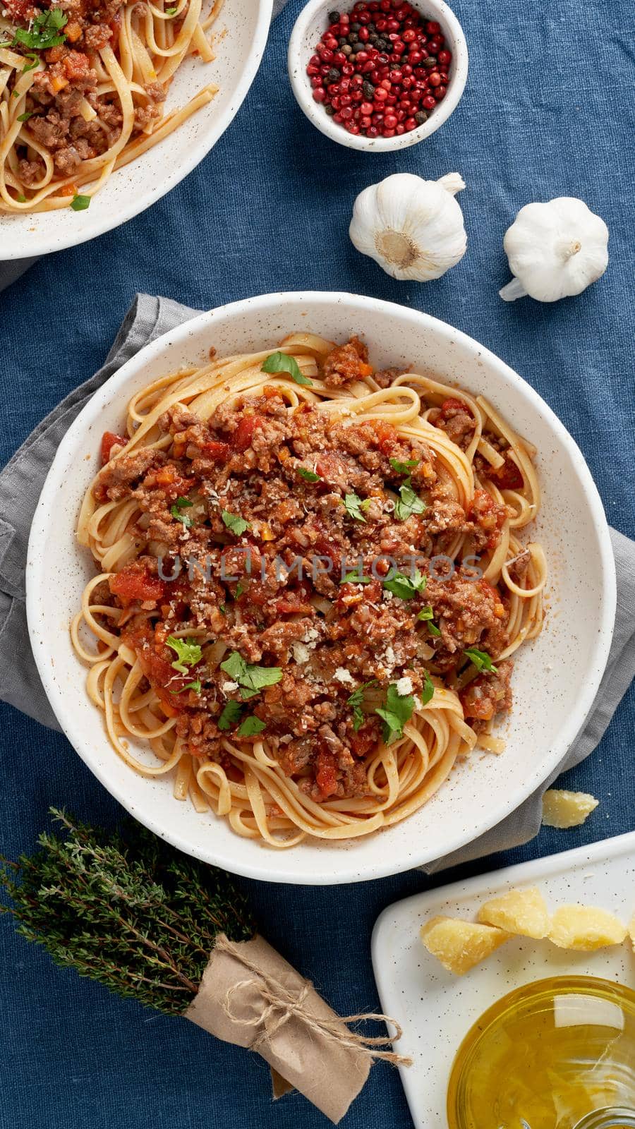 Pasta Bolognese Fettuccine with mincemeat and tomatoes, parmesan cheese. Italian dinner for two, dark blue tablecloth. Top view, vertical