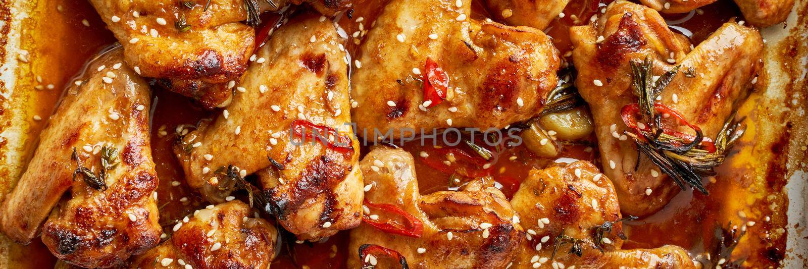 Barbecue chicken wings. Sticky asian spicy wings with teriyaki. Long width banner. Oven baked marinated chiken in metalic tray. Gray table, top view