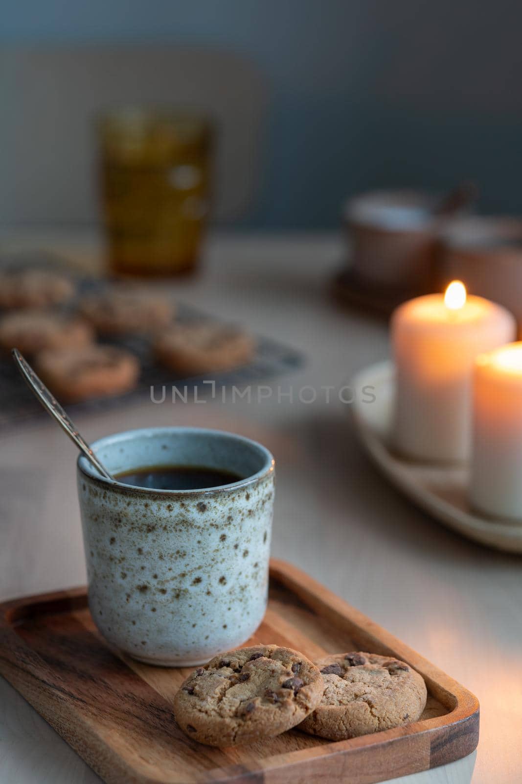 Christmas background with Chocolate chip cookies, cup of tea. Cozy evening, mug of drink, holiday decorations, candles lights bokeh. Vertical still life twilight