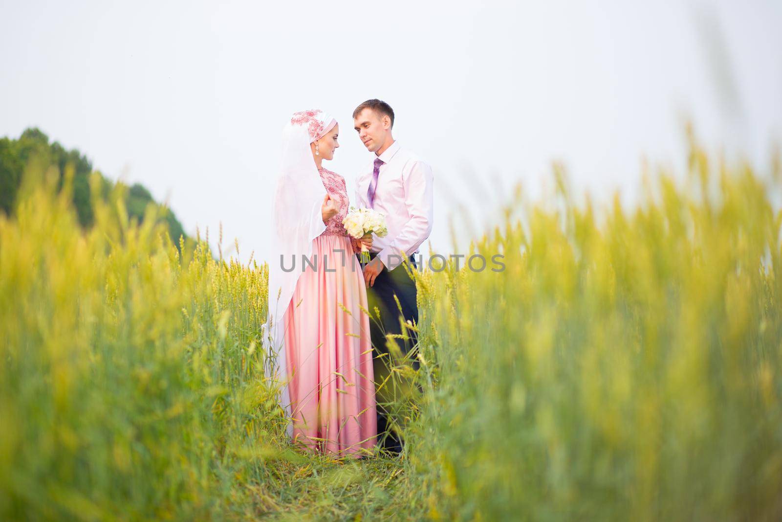 Bride and groom in field. Muslim marriage. by AlikMulikov