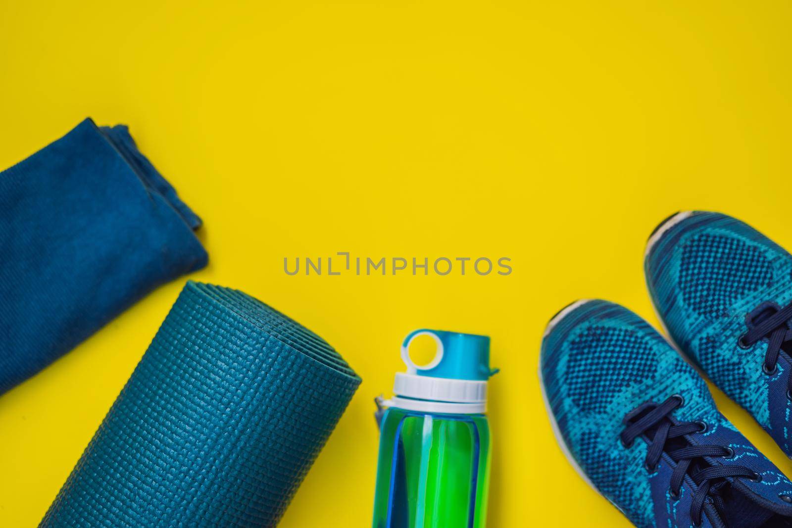 Everything for sports turquoise, blue shades on a yellow background. Yoga mat, sport shoes sportswear and bottle of water. Concept healthy lifestyle, sport and diet. Sport equipment. Copy space.