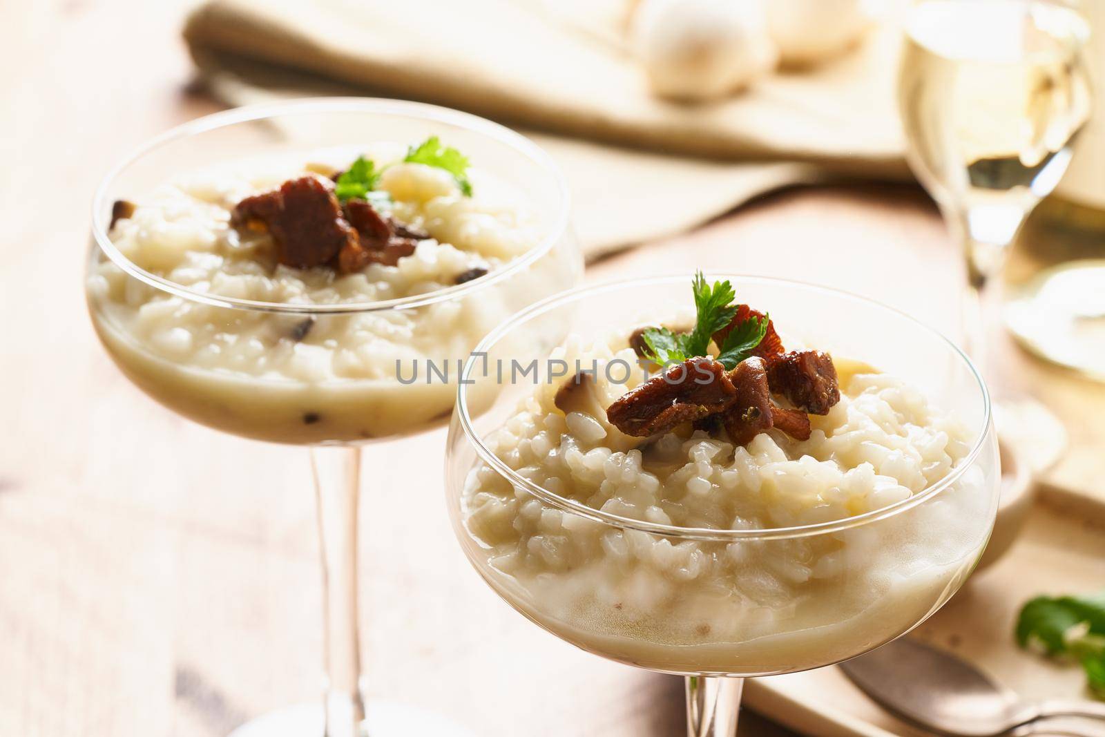 Risotto with mushrooms in wine glass. Unconventional unusual serving. Rice porridge with mushrooms. Wooden old table. Hot dish in glass bowl. Close up