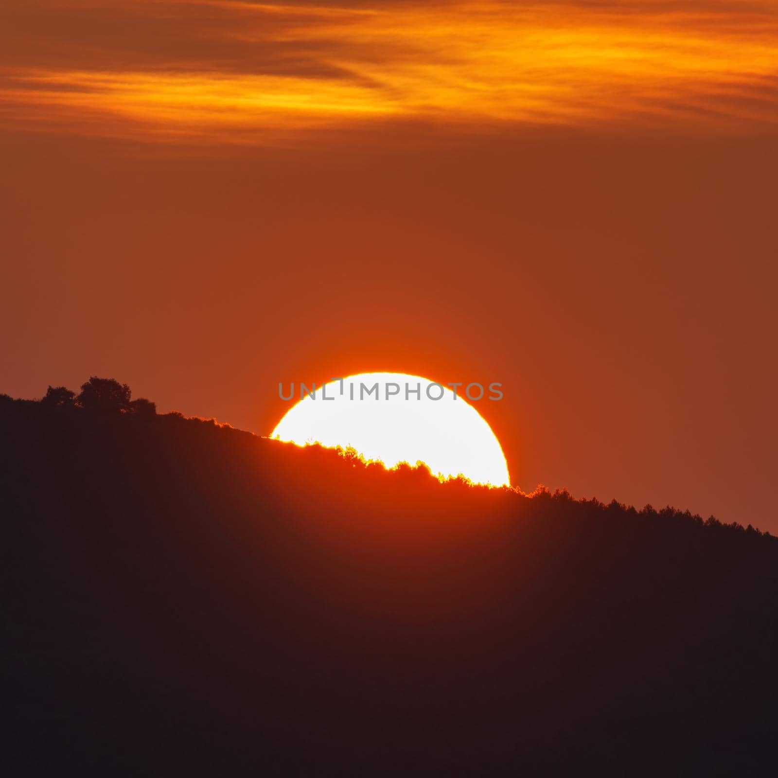 Long shot of sun behind mountain at sunrise