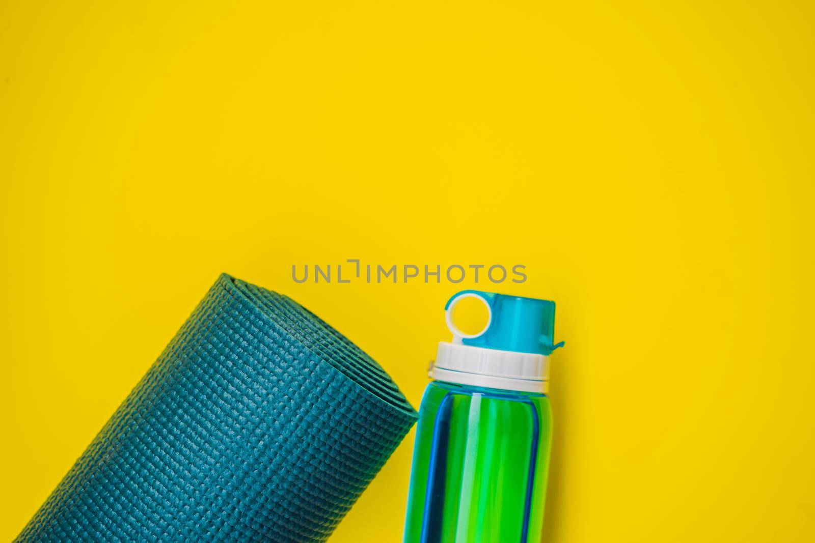 Everything for sports turquoise, blue shades on a yellow background. Yoga mat, sport shoes sportswear and bottle of water. Concept healthy lifestyle, sport and diet. Sport equipment. Copy space by galitskaya