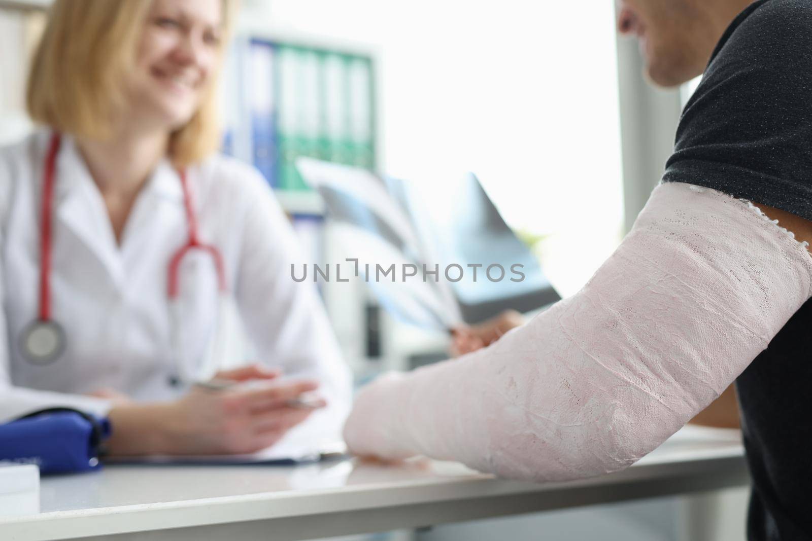Male patient with bandage on his arm sitting at traumatologist appointment closeup by kuprevich