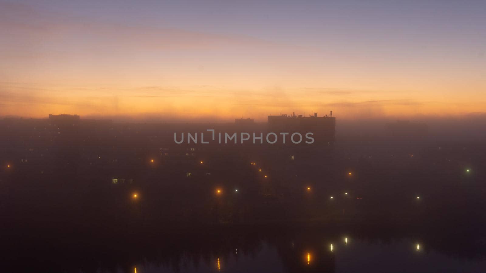 SEVERODVINSK, RUSSIA - MARCH, 11, 2021: Bright winter sunset against the background of houses. Multi-story houses in the rays of the sun. The sun goes down behind the houses