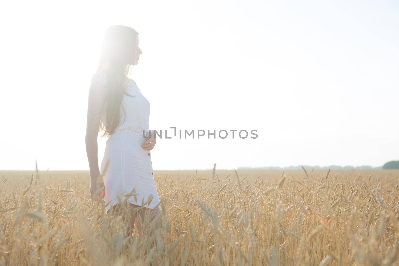 Pretty young woman in field at sunset. by AlikMulikov