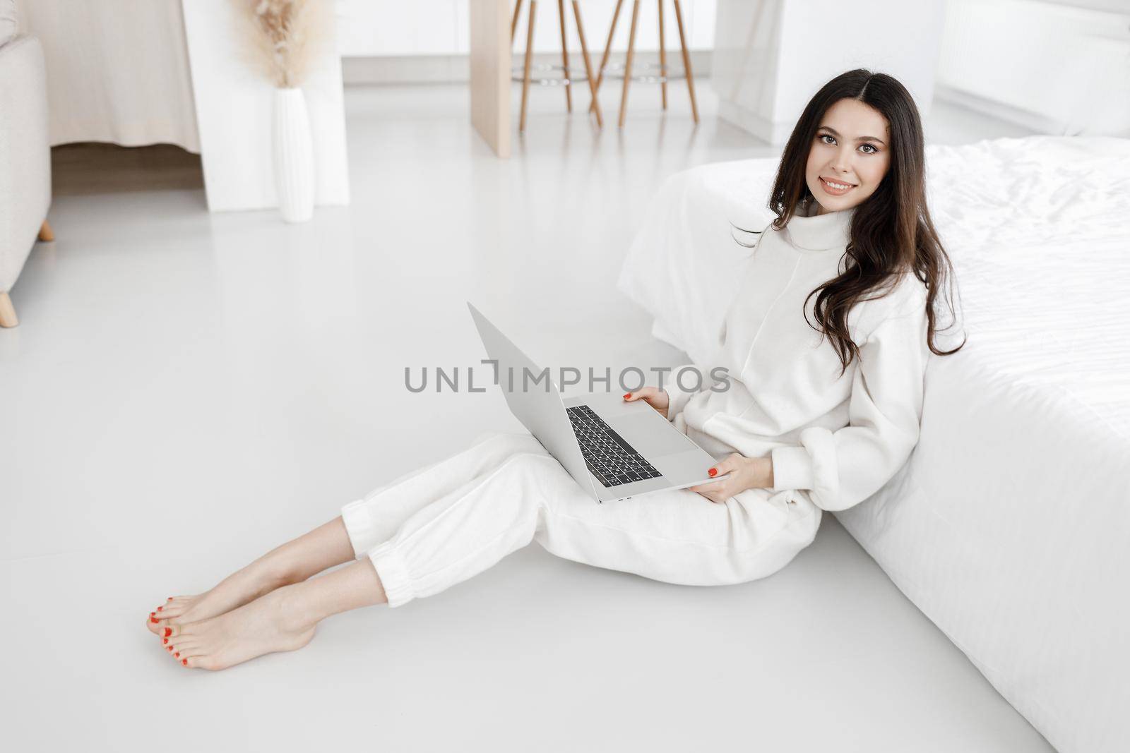 young woman working in laptop at home indoor in white colours. High quality photo