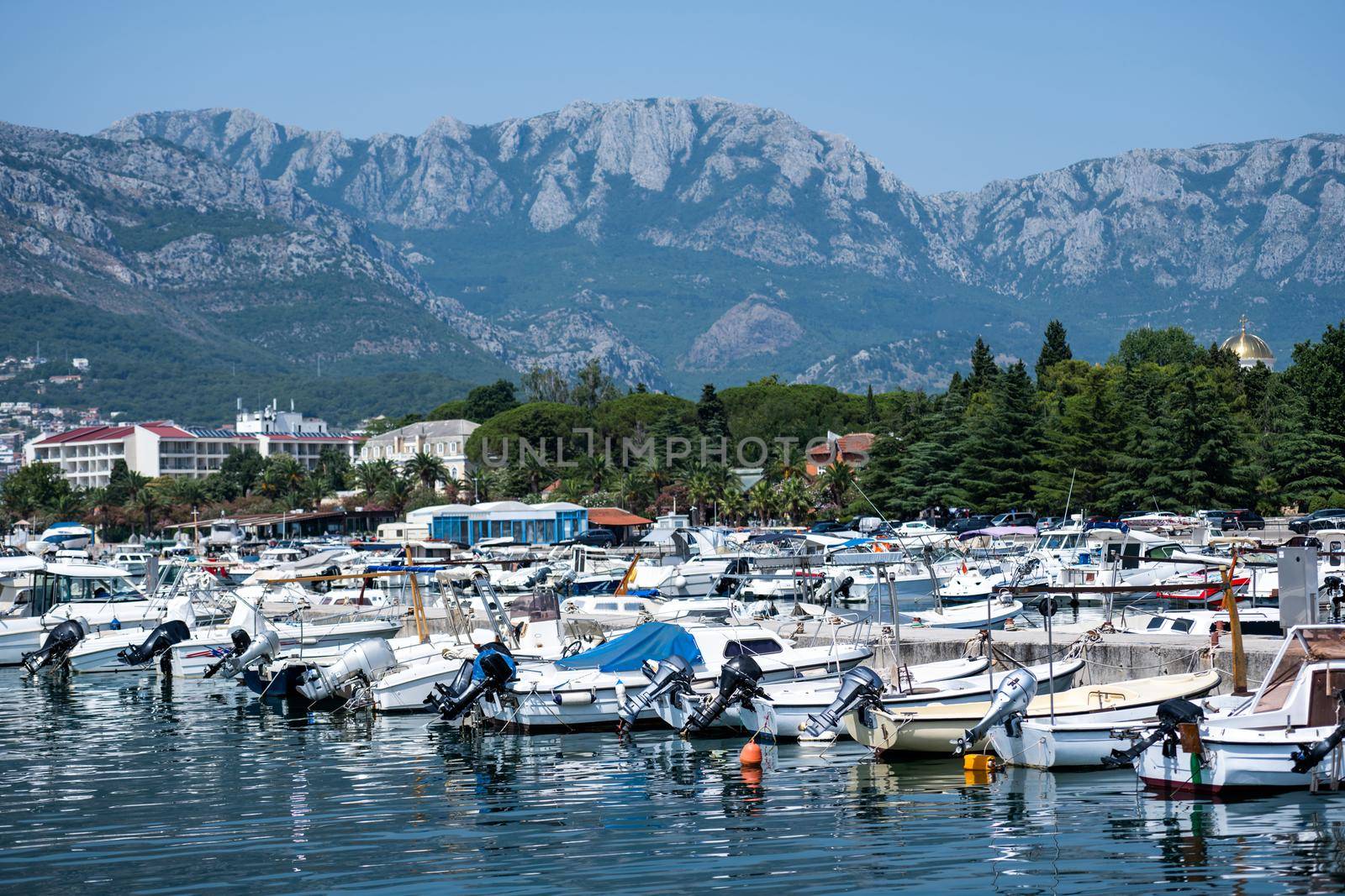 Yachts port in Montenegro with mountains and city view in adriatic sea. Boats pier in sunny day with beautiful Mediterranean nature
