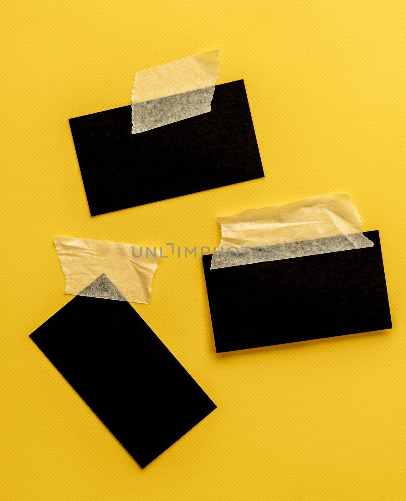 Black business cards with copy space attached with tape on yellow background. Identity blank for commercial using and branding
