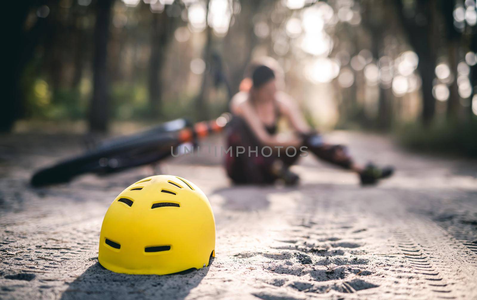 Protective helmet on forest road on background of woman fell from bicycle