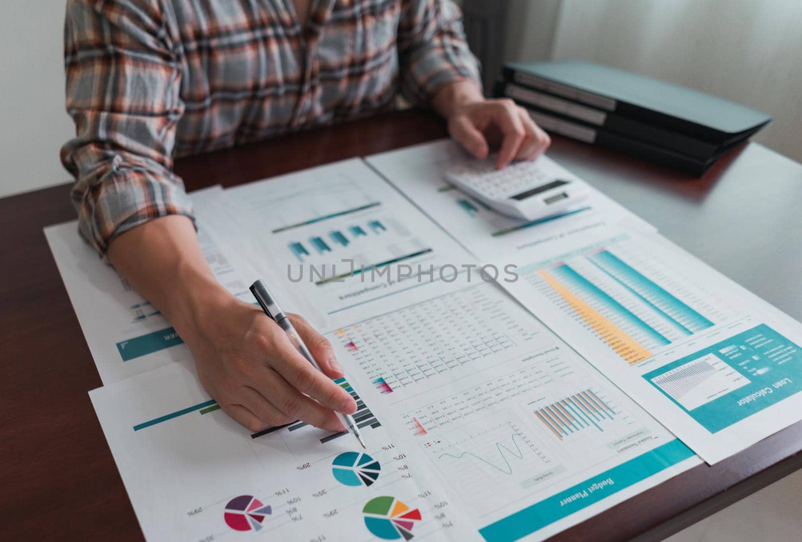 Businessman calculates and analysis chart statistics about tax, accounting, math finance, on wooden desk in the office. by pravinrus