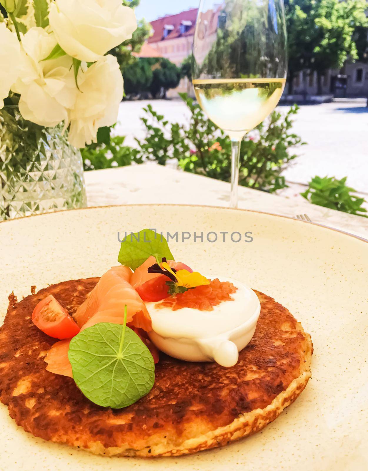 Potato fritter pancake with red caviar, salmon and sour cream in luxury restaurant outdoors in summer by Anneleven