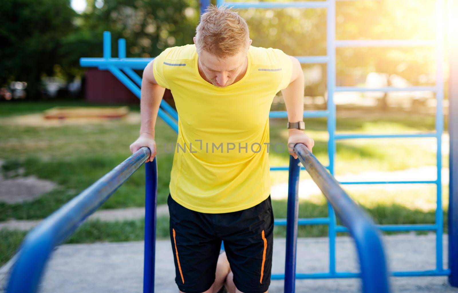 Man pulling up on parallel bars during street training