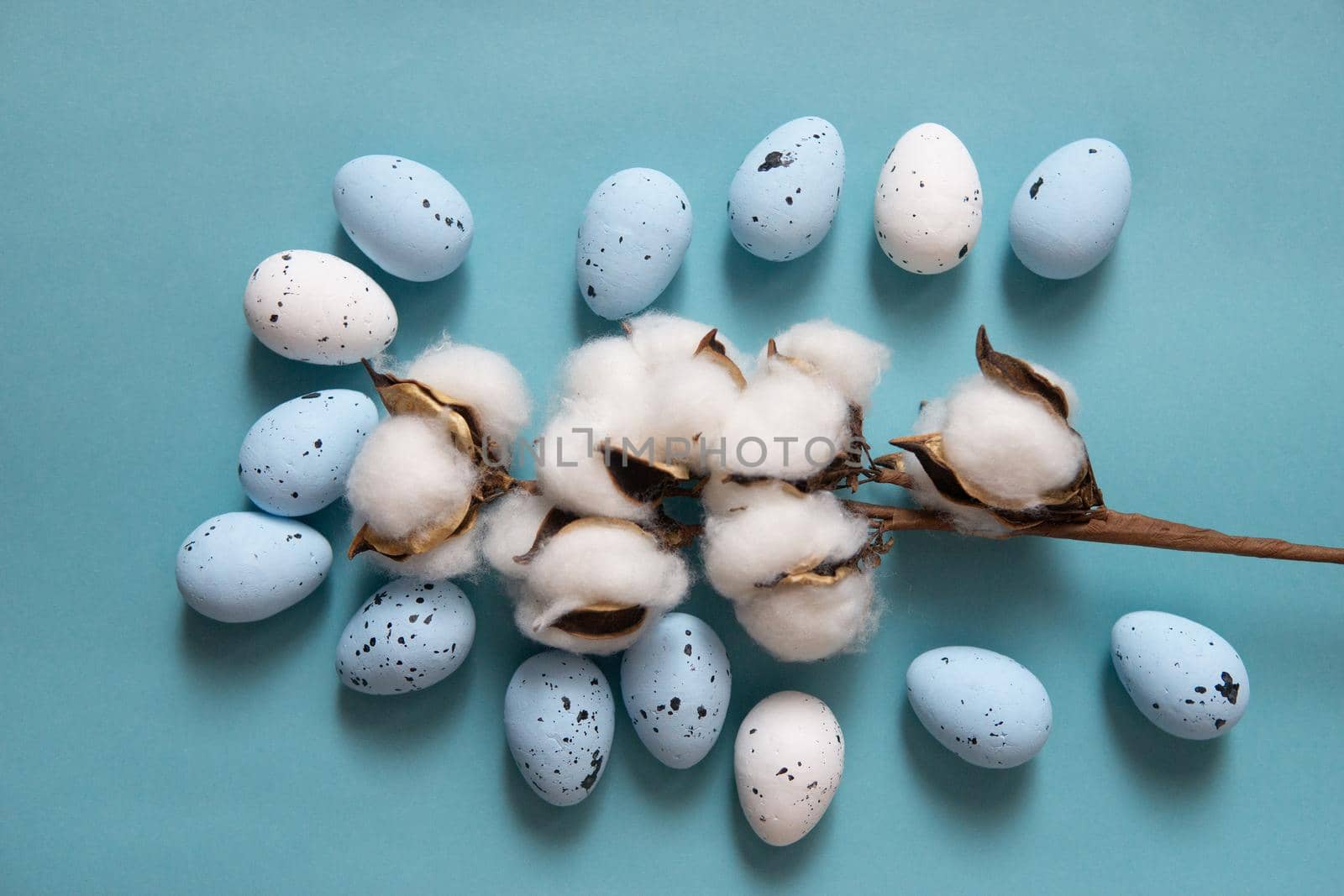 Easter background. Blue and white painted quail eggs on a blue background, decorated with cotton. Happy Easter holiday.