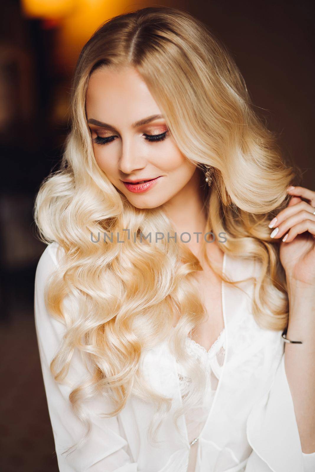 Portrait of beautiful and charming blondie bride, looking and smiling at camera. Beautiful sexy lady with pure skin, long hair posing in morning at bedroom. Wedding concept and preparing.